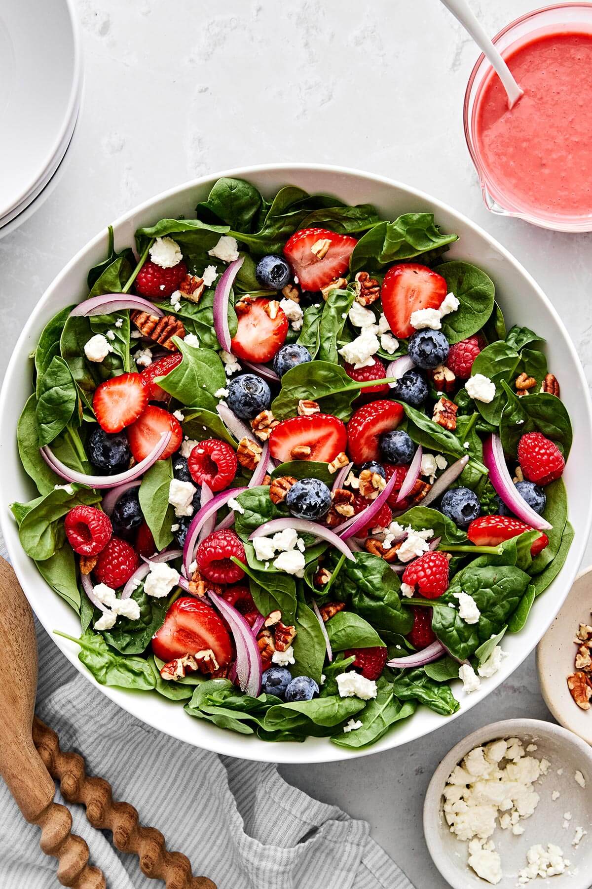 A bowl of berry spinach salad with strawberries, raspberries, and blueberries.