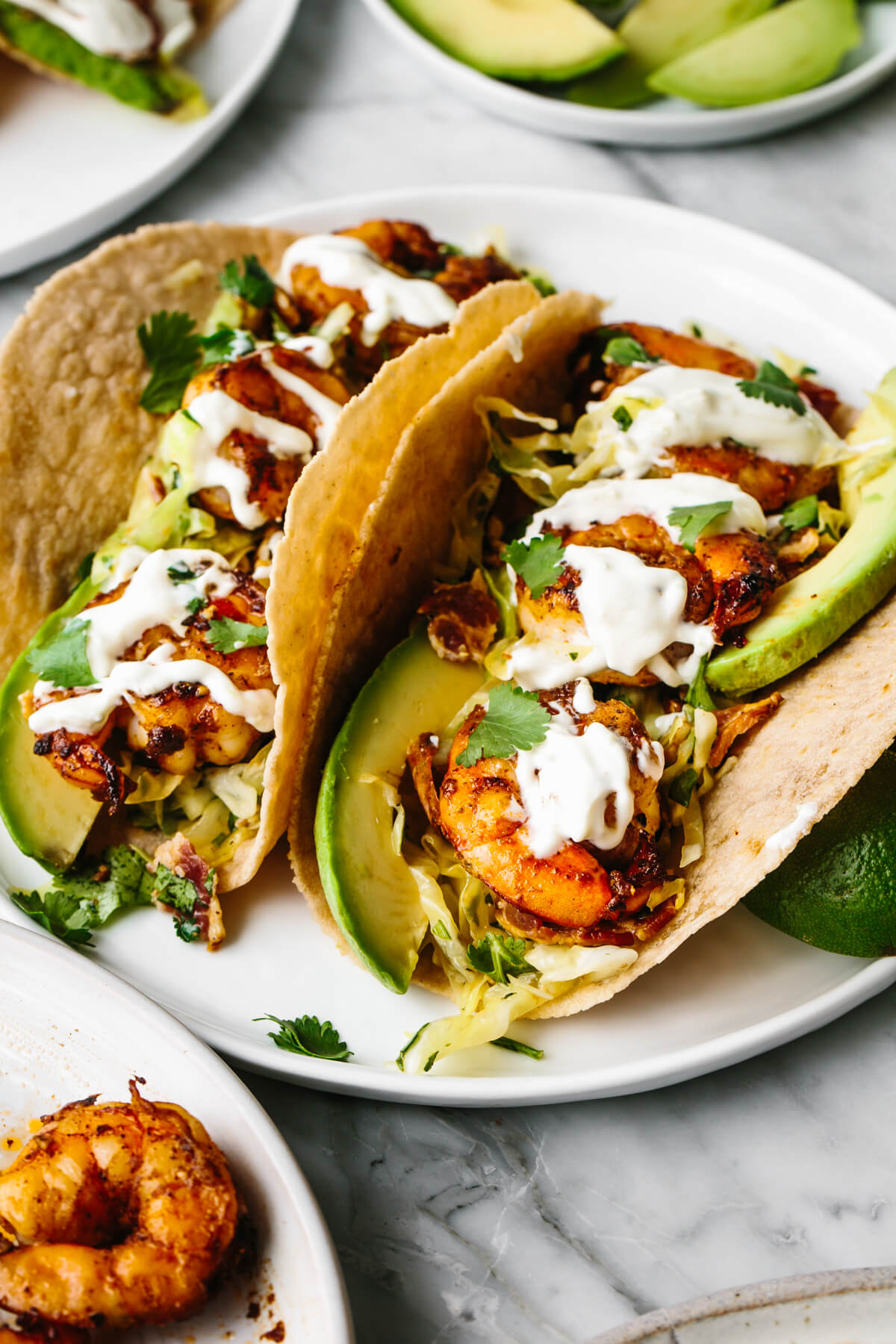 Shrimp tacos on a plate next to avocado