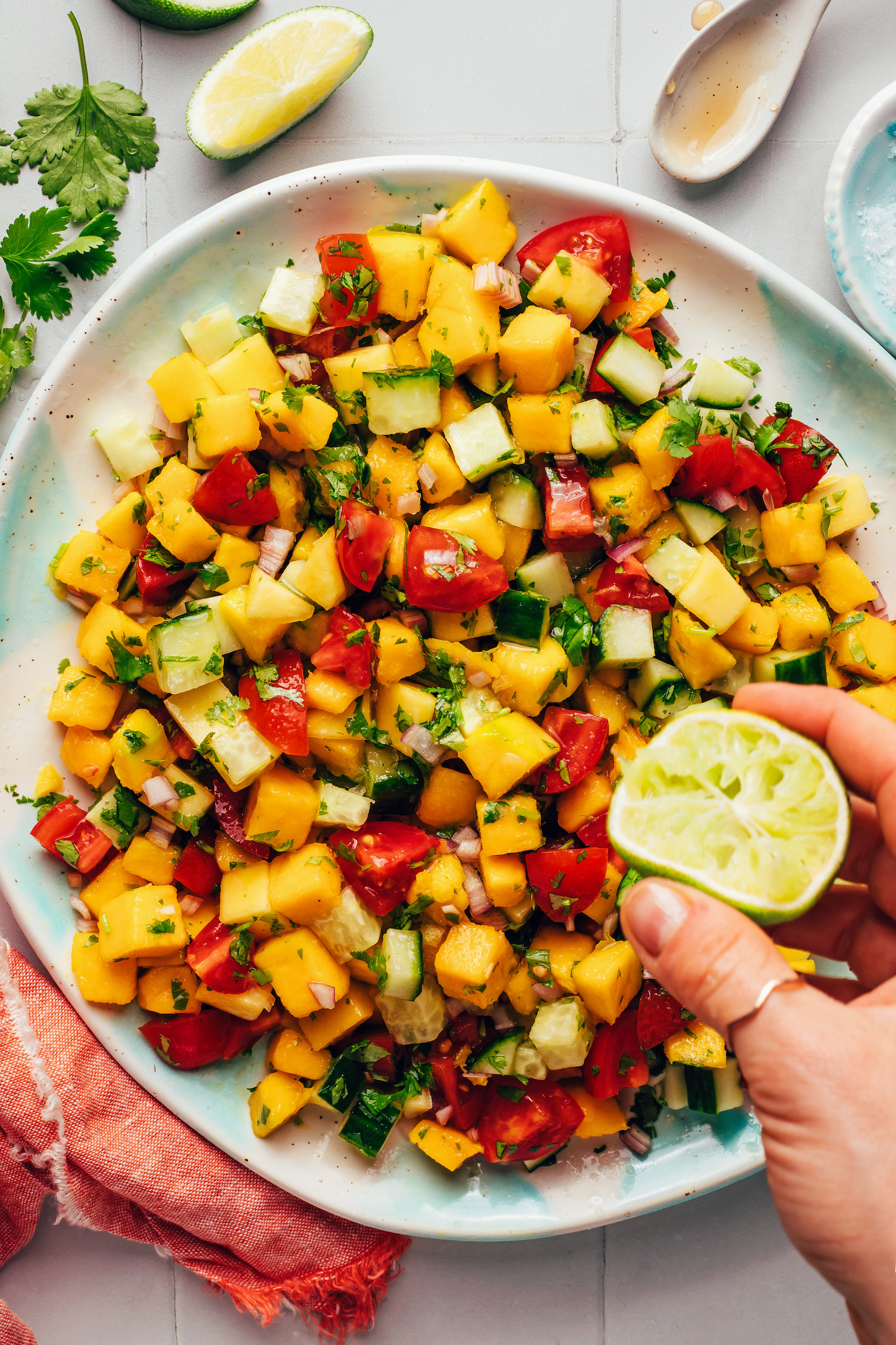 Squeezing fresh lime juice onto a plate of mango cucumber salad