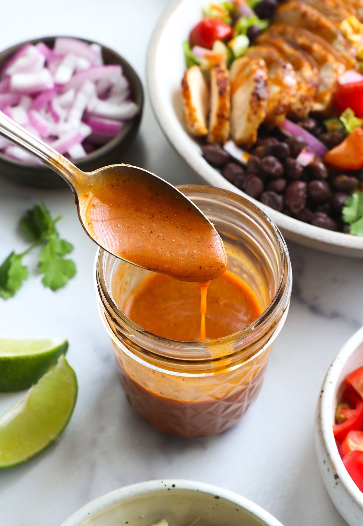 honey chipotle vinaigrette dripping off a spoon into a jar.