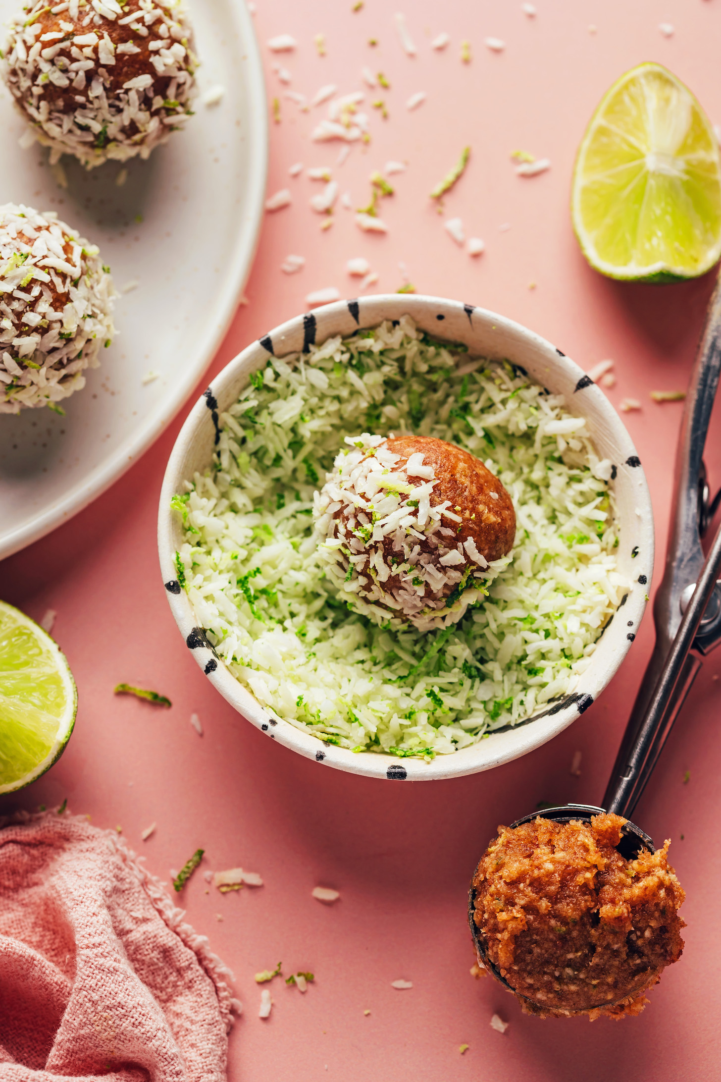 An energy bite resting in a bowl of shredded coconut and lime zest