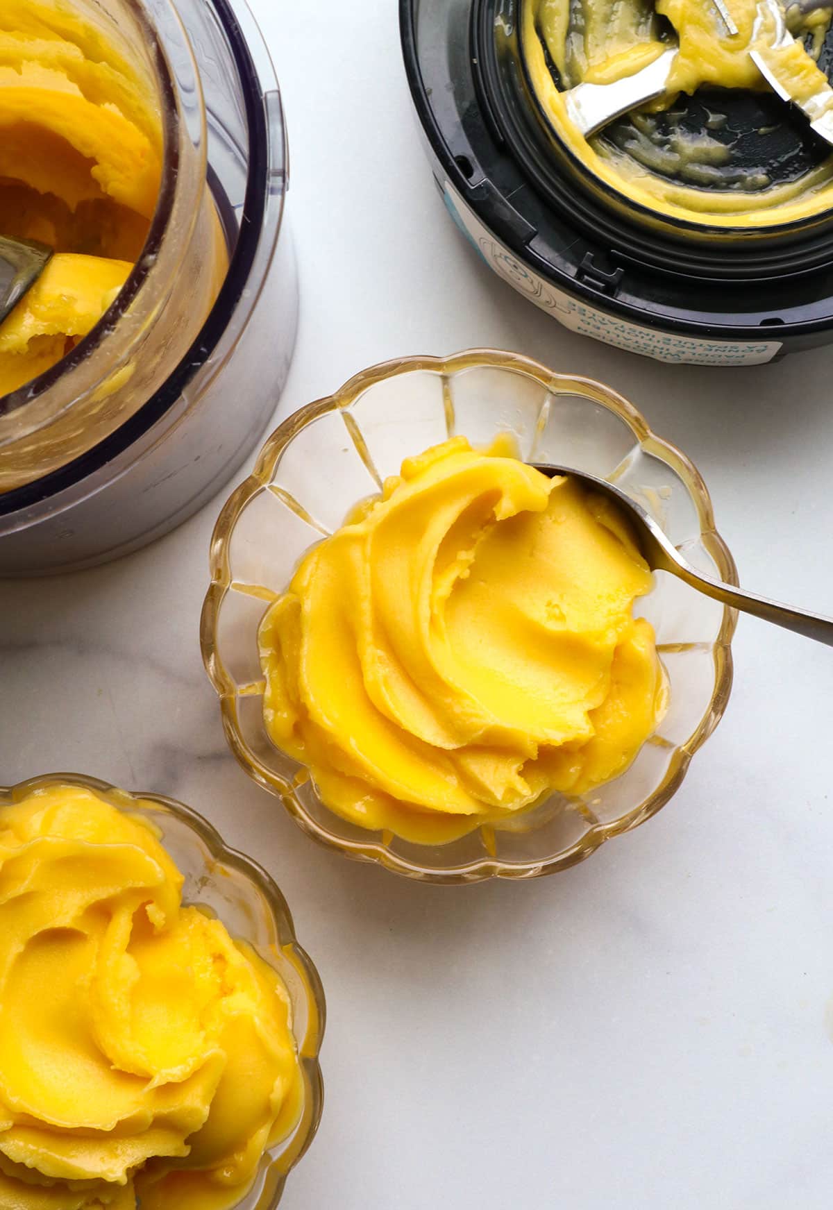 mango sorbet in two glass bowls by the Ninja Creami.