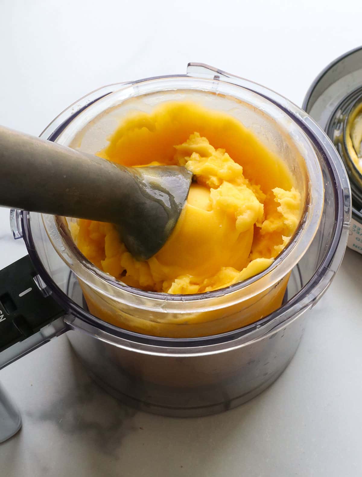 mango sorbet with an ice cream scoop in the Ninja creami bowl.