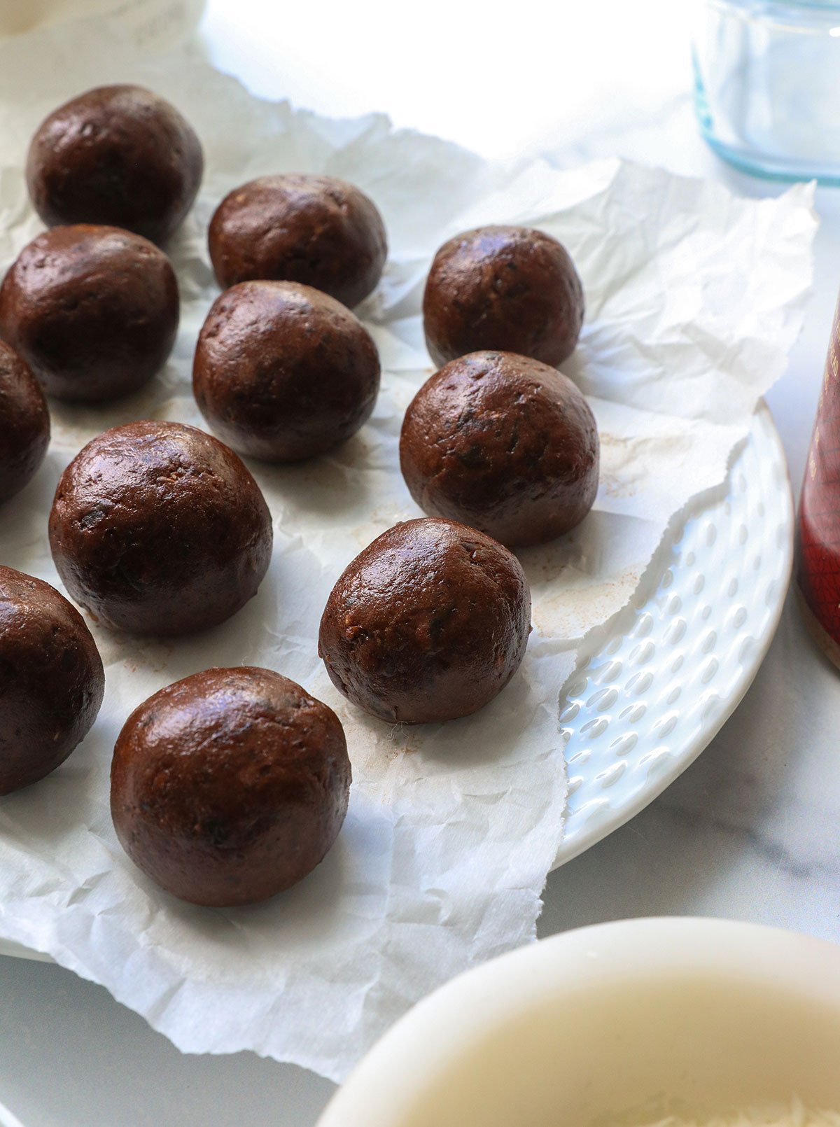 chocolate protein balls on a parchment lined plate.