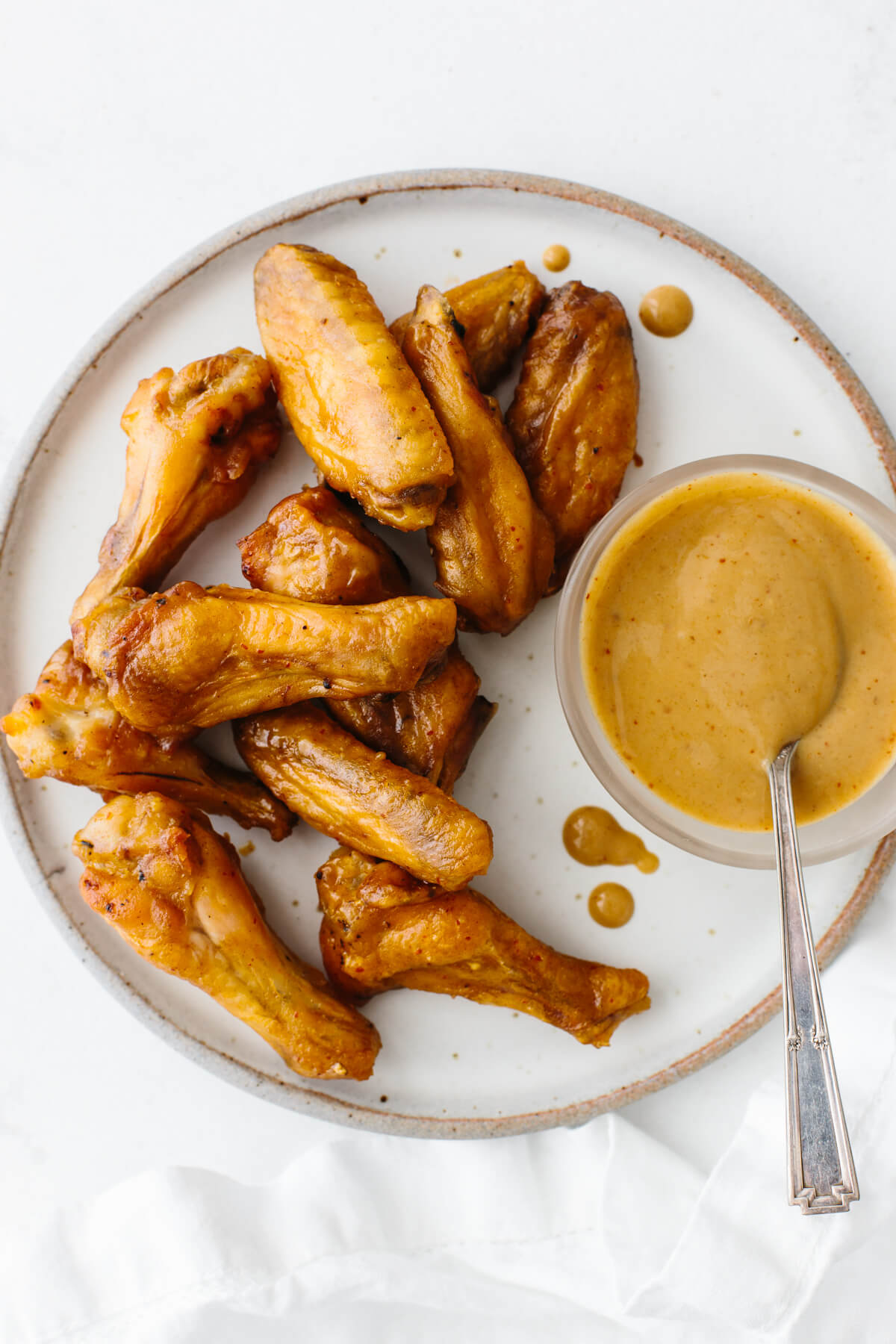 Honey mustard chicken wings on a plate with sauce.