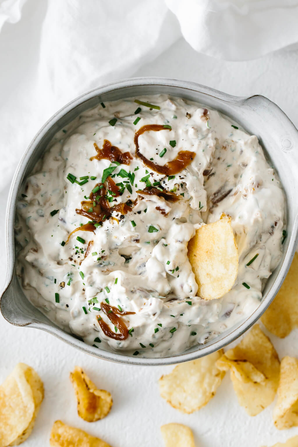 French onion dip with a potato chip scooping it up.