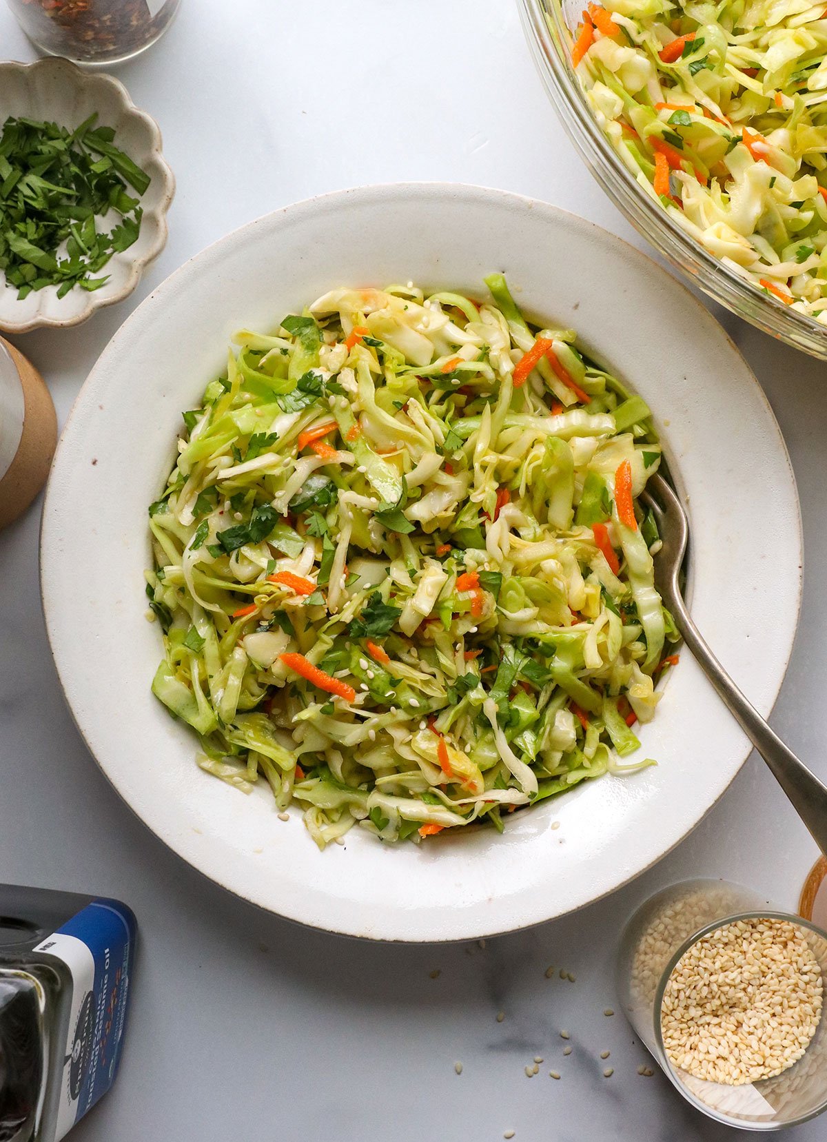 Asian slaw served in a white bowl with a fork.