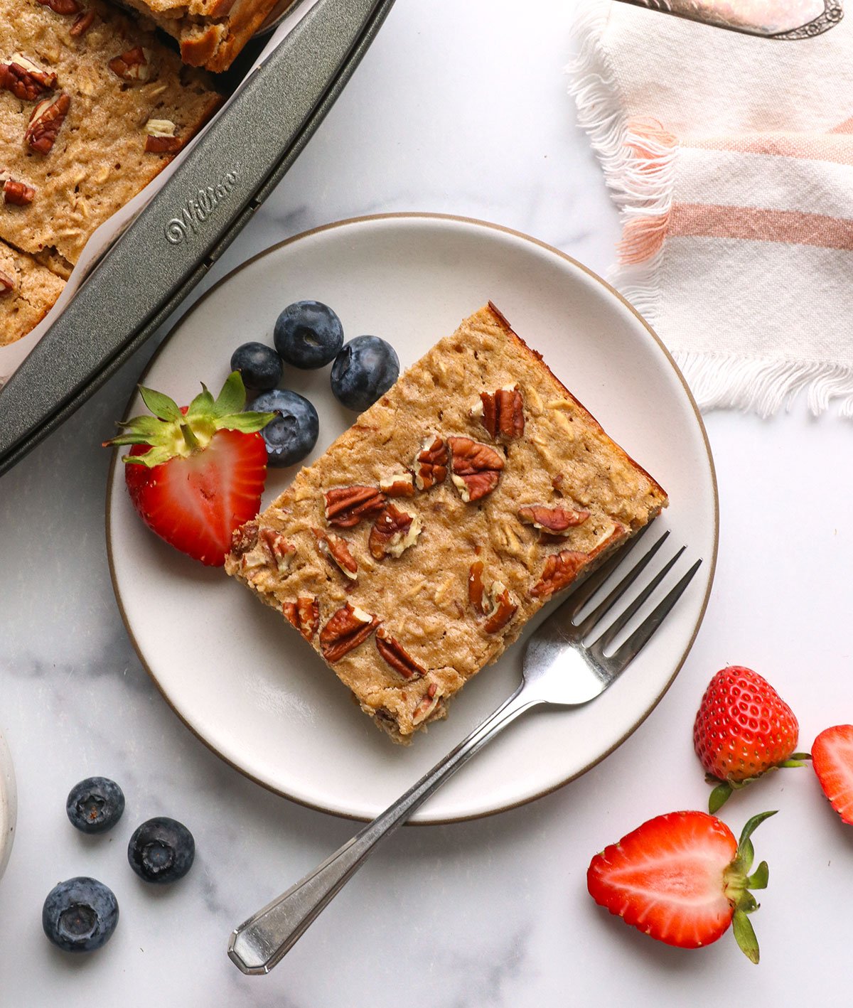 slice of protein baked oatmeal on a plate with berries.