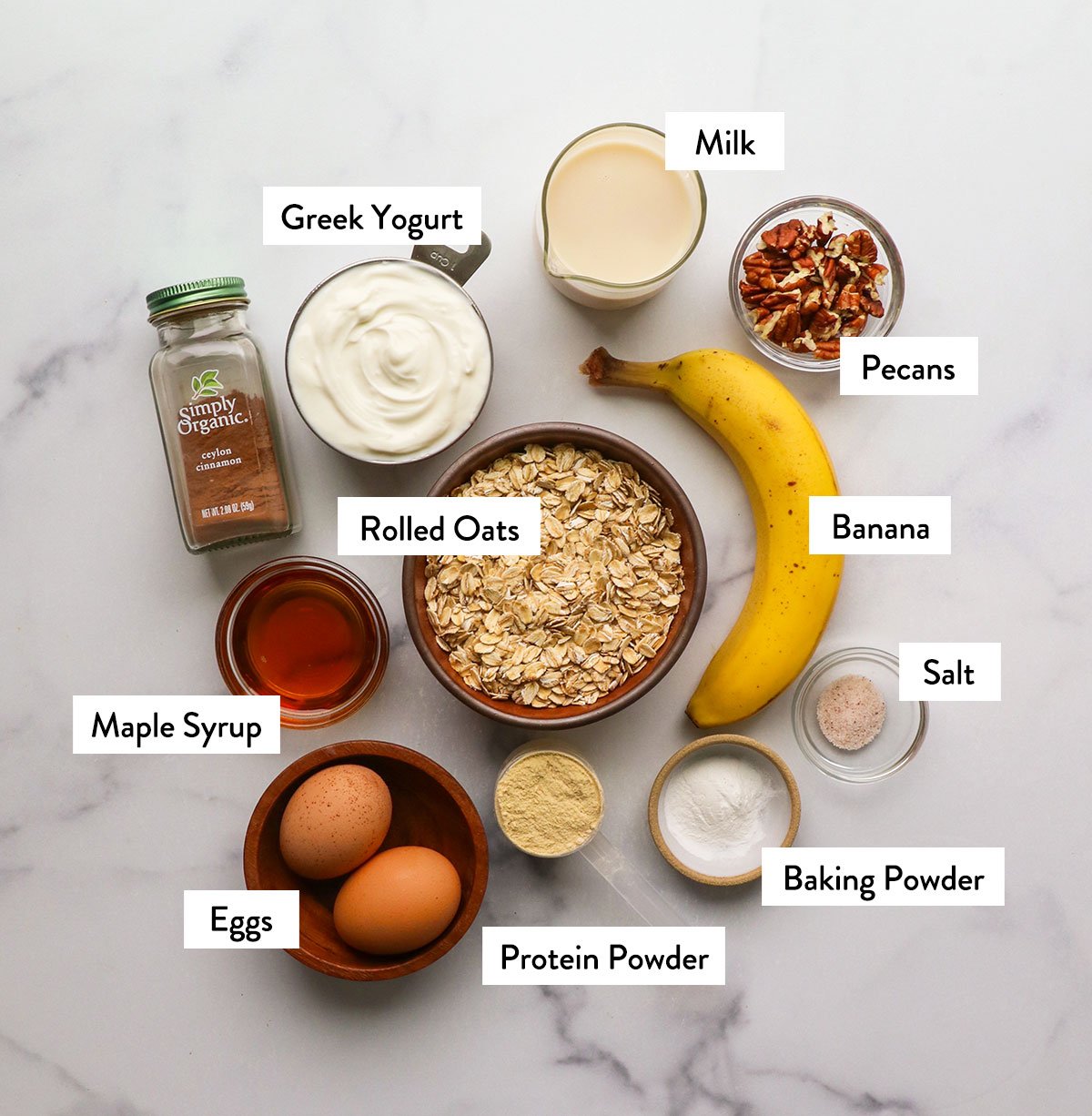 rolled oats, banana, eggs, maple syrup, yogurt, and milk labeled in bowls.