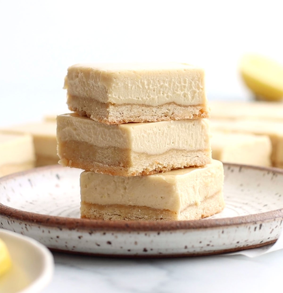 vegan lemon bars stacked on a white plate.