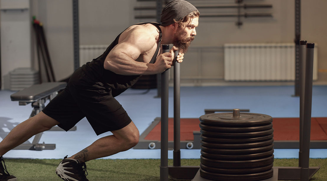 Strong muscular man performing a sled exercise