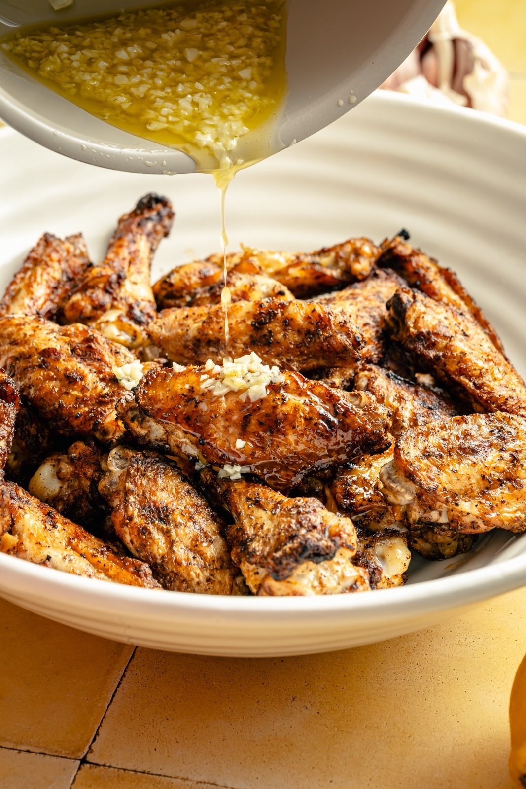 pouring lemon butter sauce onto lemon parmesan chicken wings