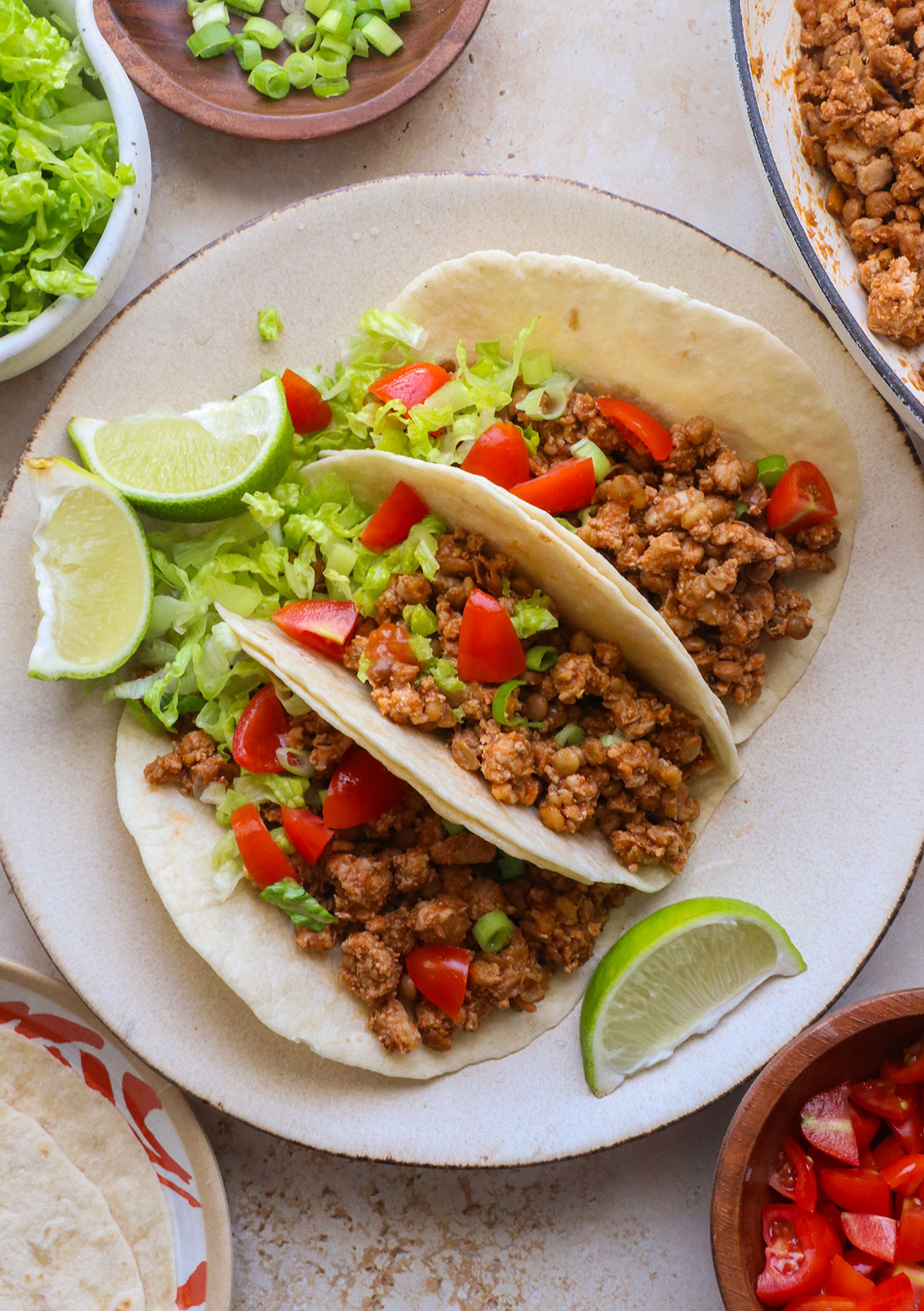 three turkey tacos on a plate with lettuce and tomatoes.