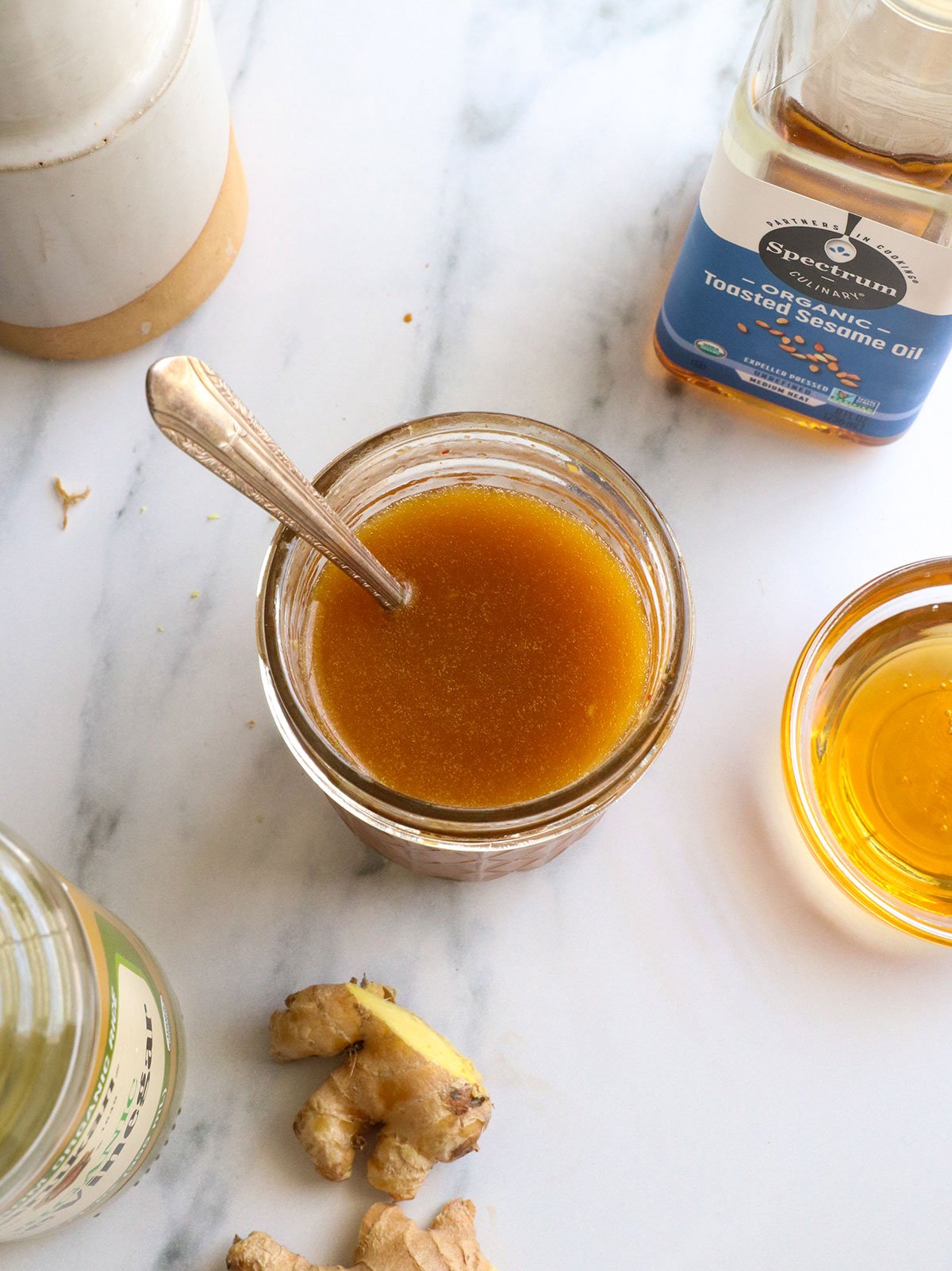 dressing mixed with a spoon near fresh ginger.
