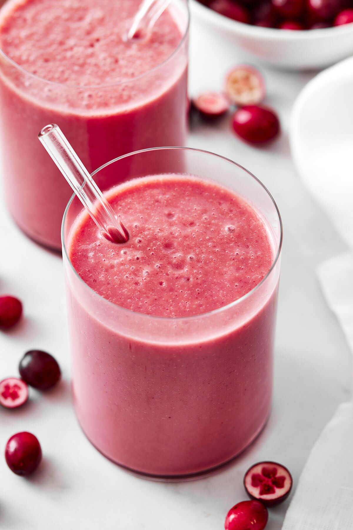 A glass of cranberry smoothie with a straw
