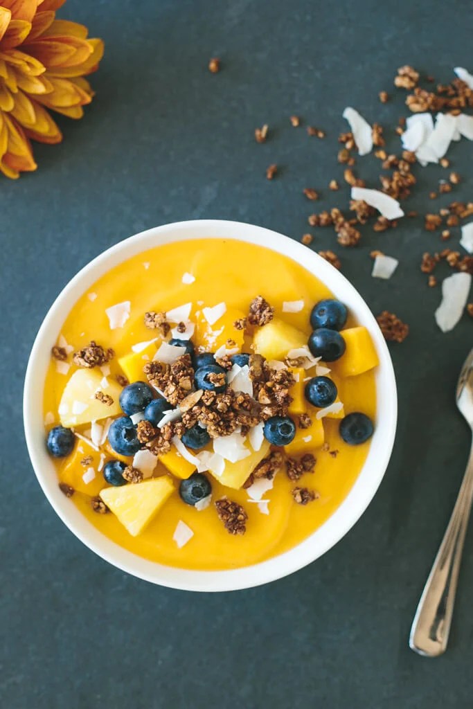 (gluten-free) Mango Smoothie Bowl. The perfect summer smoothie bowl, filled with mangoes, pineapple, blueberries and gluten-free granola.