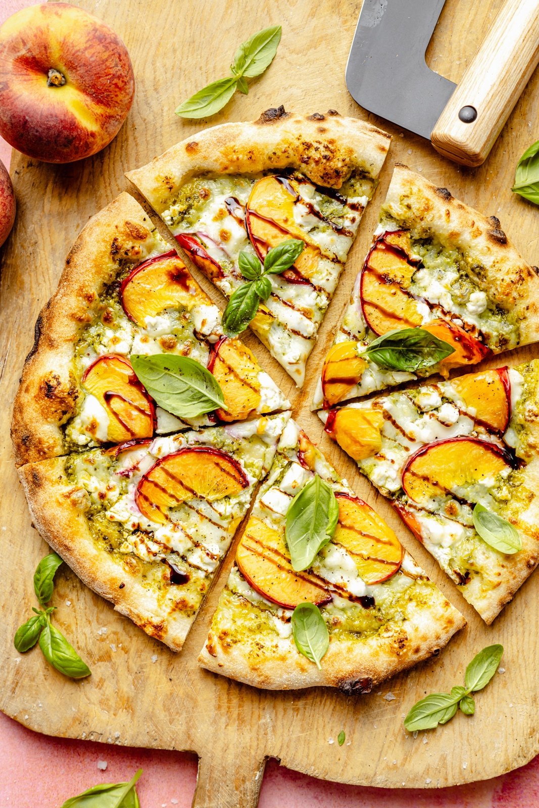 pesto peach pizza sliced on a cutting board