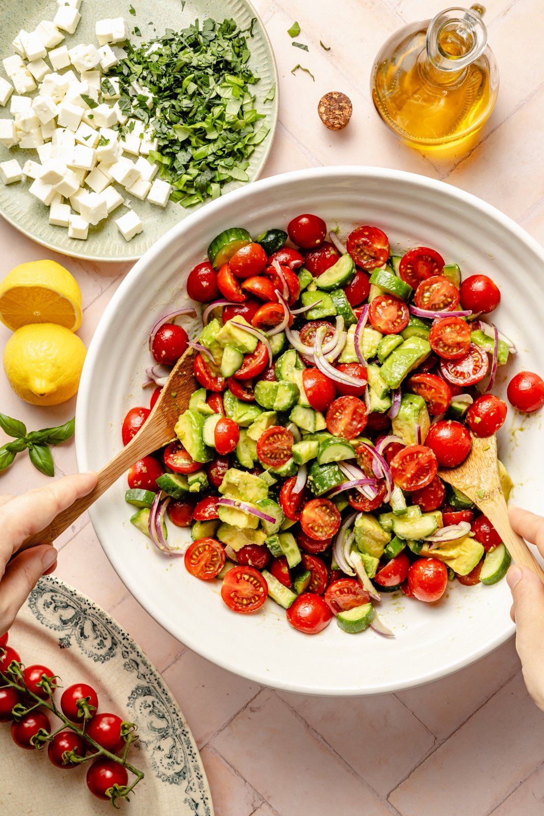 tossing a fresh tomato cucumber salad in a bowl