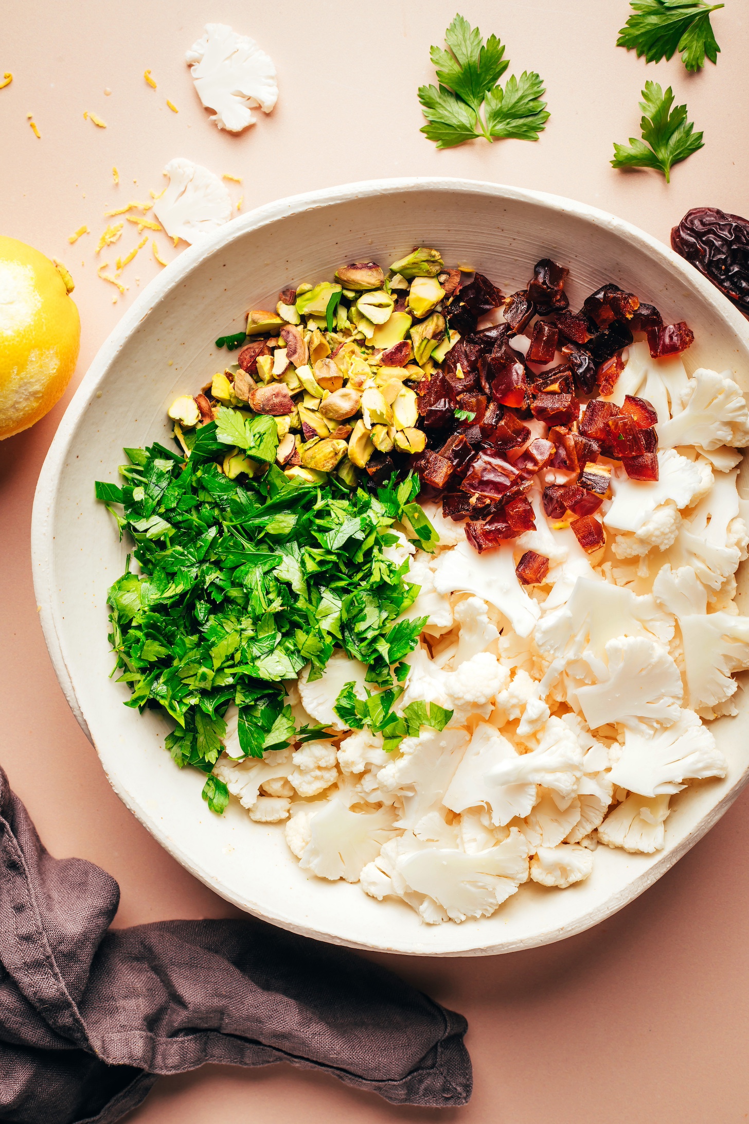 Bowl of thinly sliced cauliflower and chopped dates, pistachios, and parsley