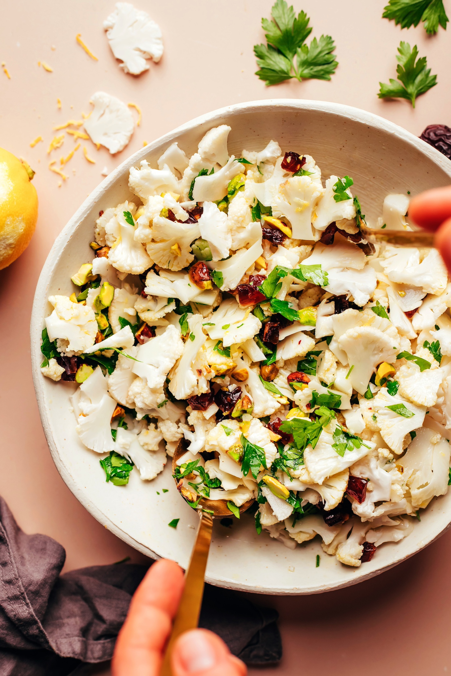 Using a fork and spoon to mix a bowl of our easy raw cauliflower salad