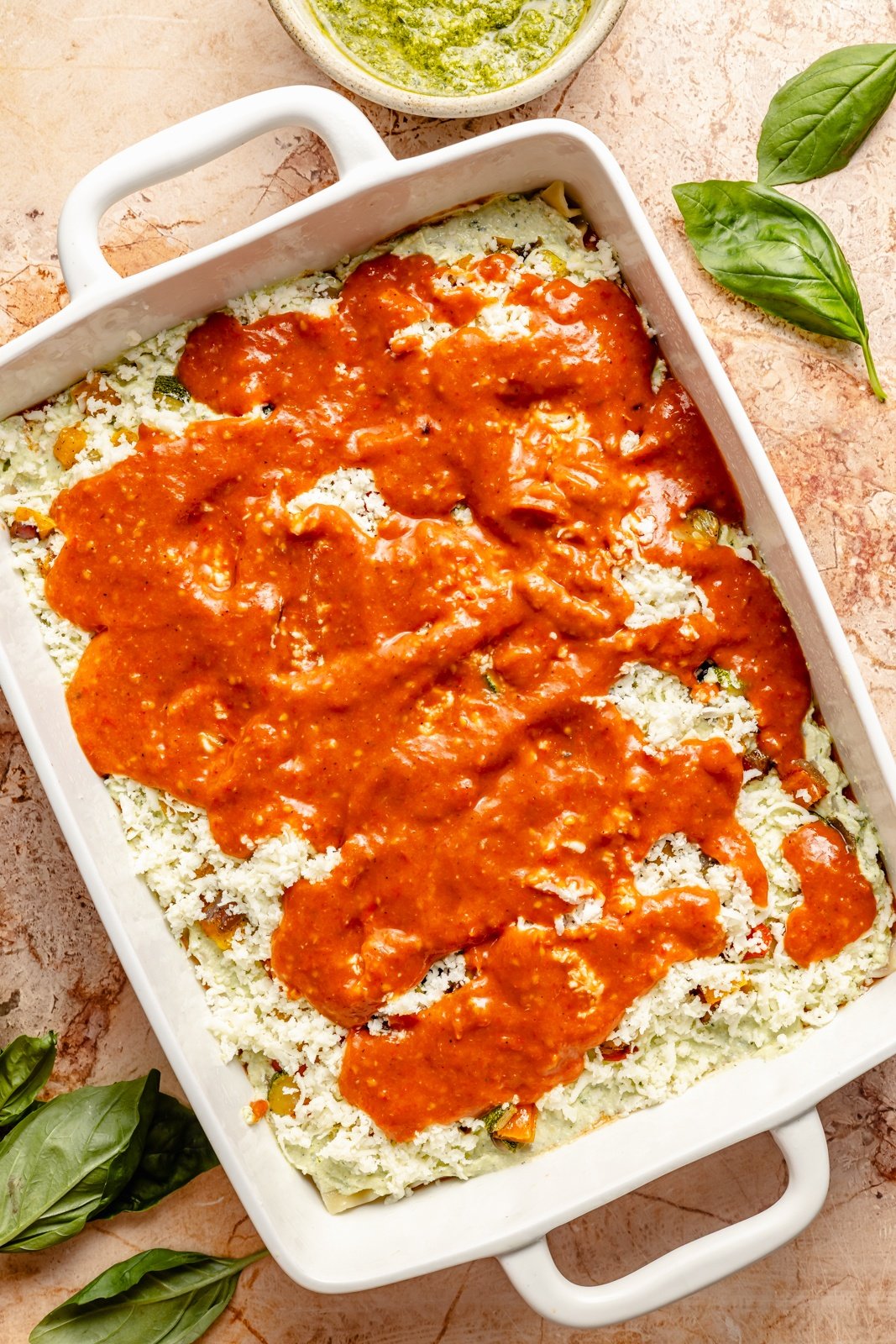 adding tomato sauce to an easy vegetarian lasagna in a pan