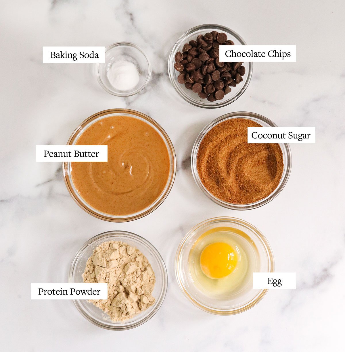 protein cookie ingredients labeled on a white surface.