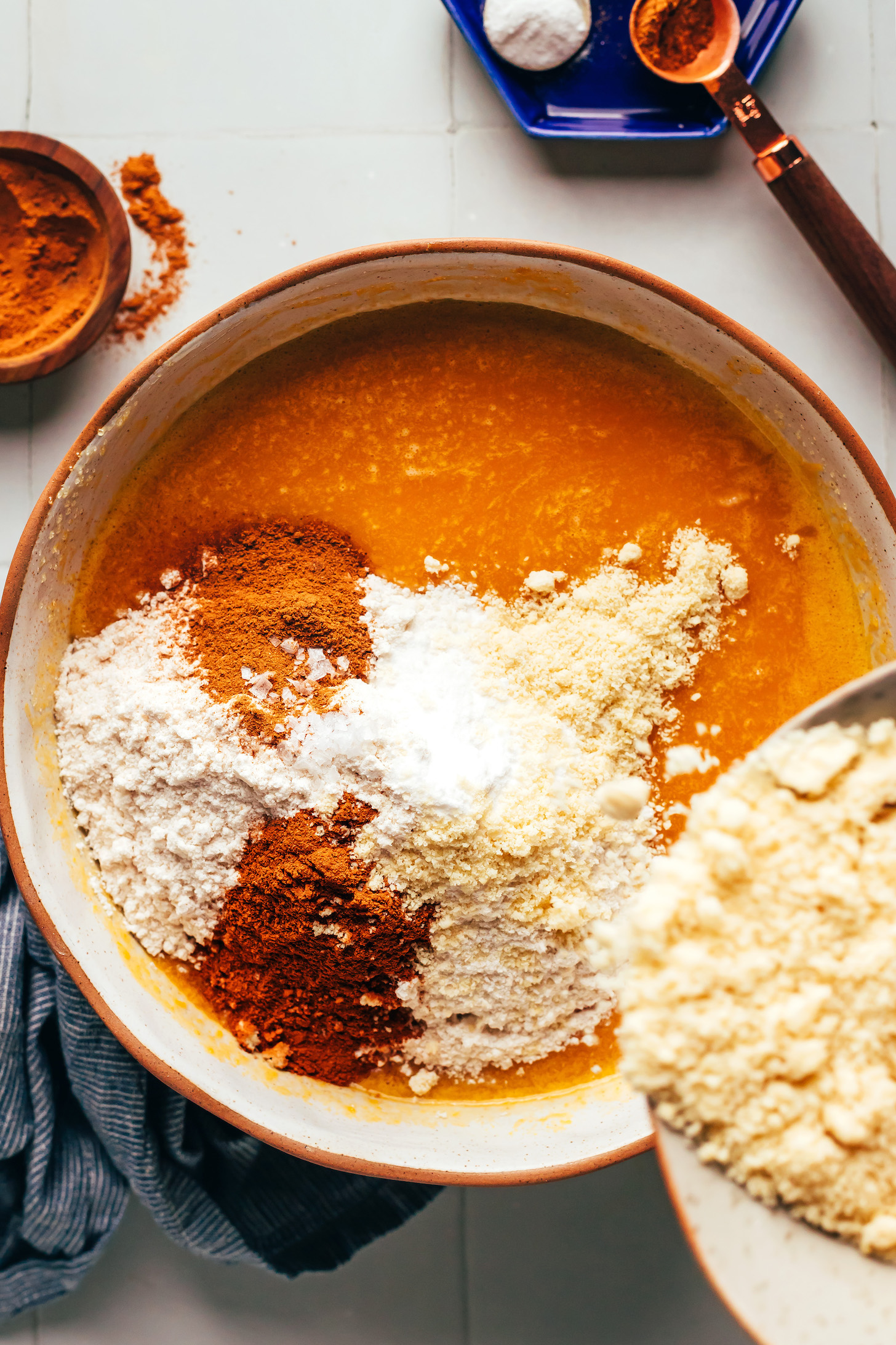 Pouring almond flour into a bowl with wet and dry ingredients