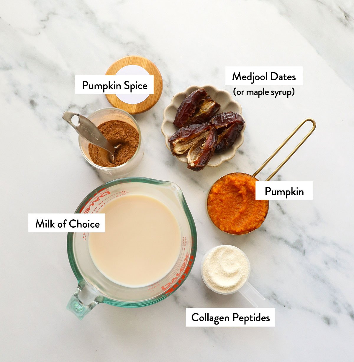 milk, pumpkin puree, dates, spice, and collagen labeled on a white surface. 