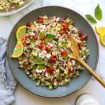 lemon orzo salad served in a blue bowl with lemon slices.