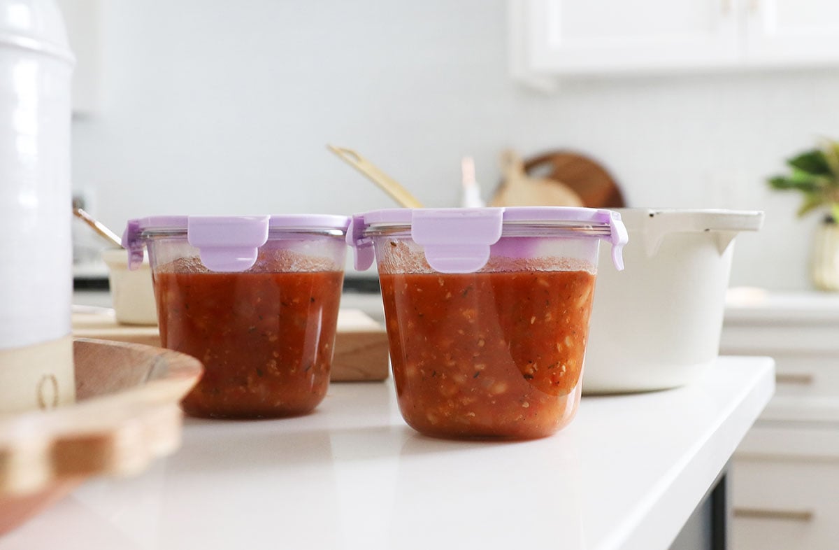 soup stored in individual glass containers on a white counter. 