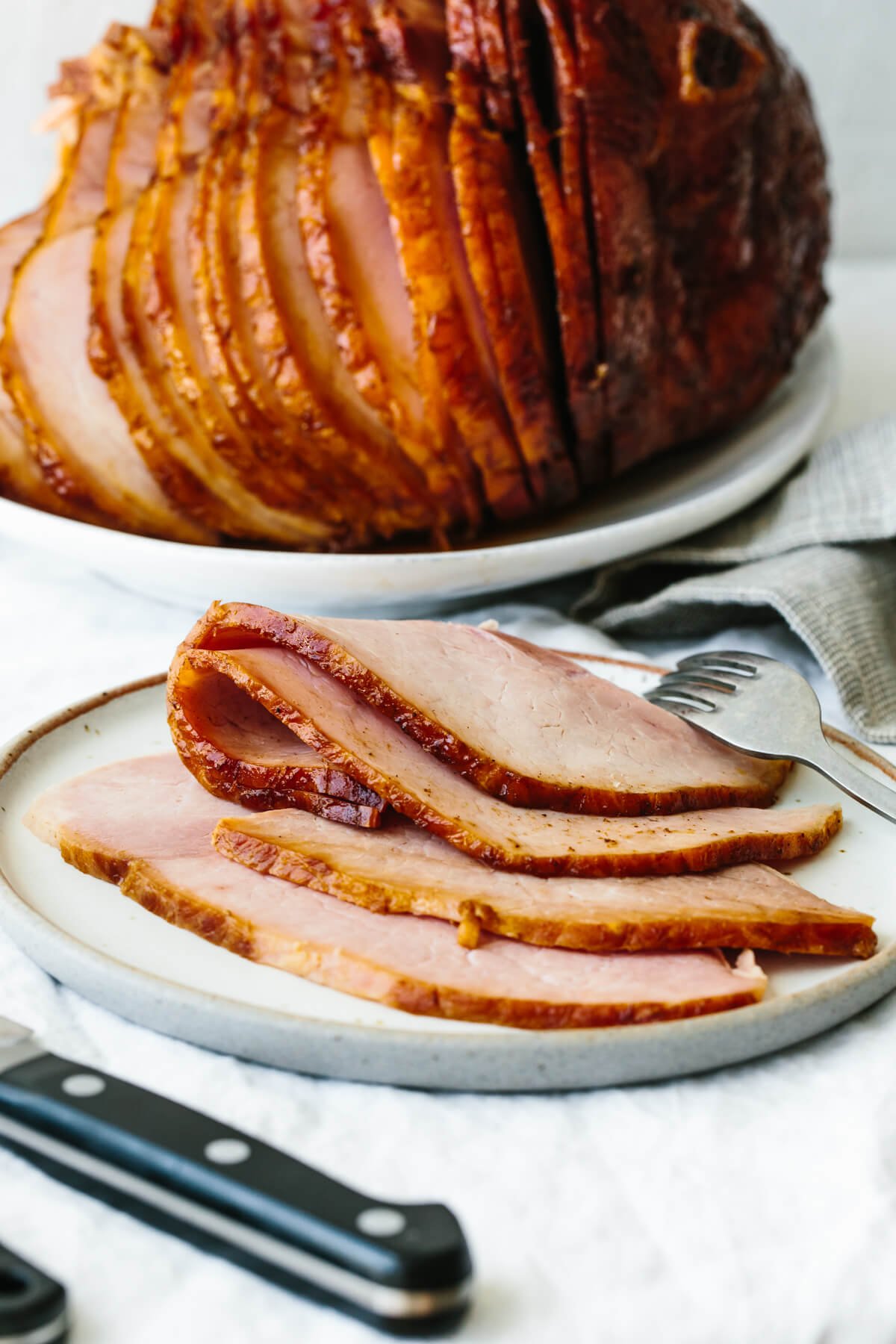 Sliced honey baked ham on a plate with a fork
