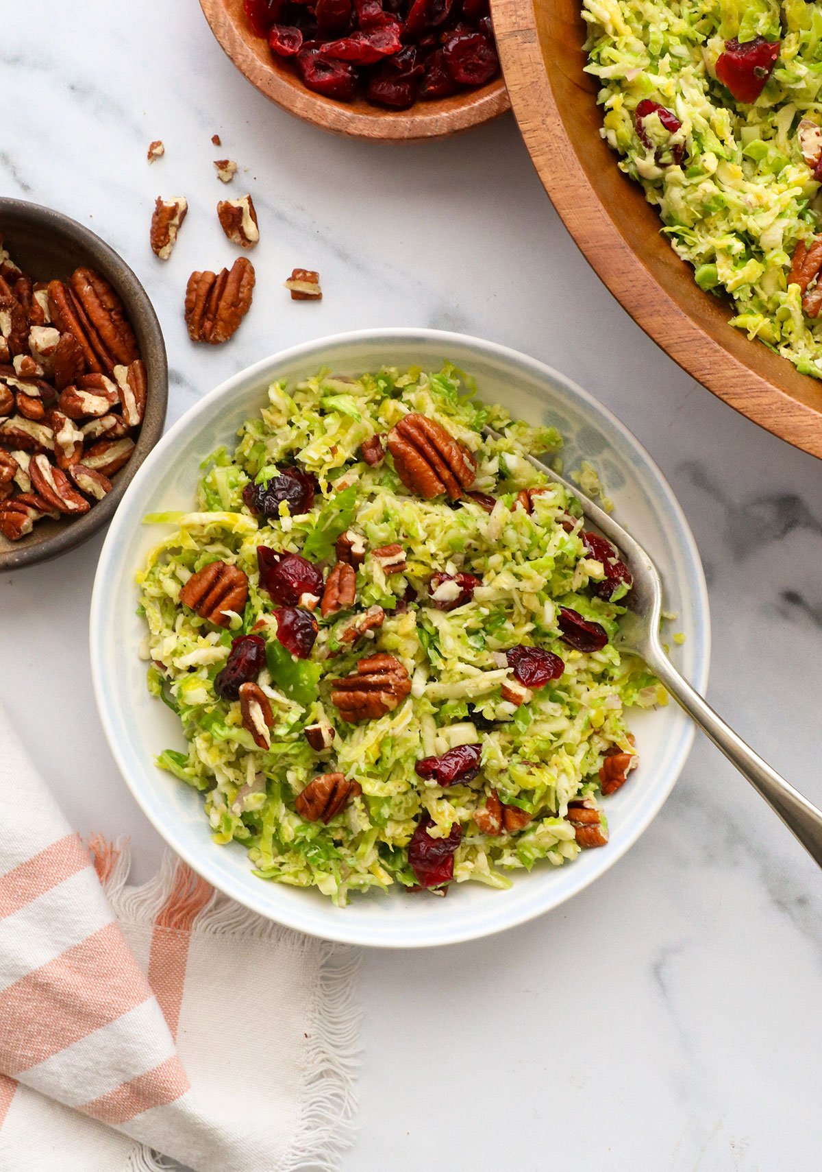 shaved brussels sprouts salad served in a white bowl with cranberries. 