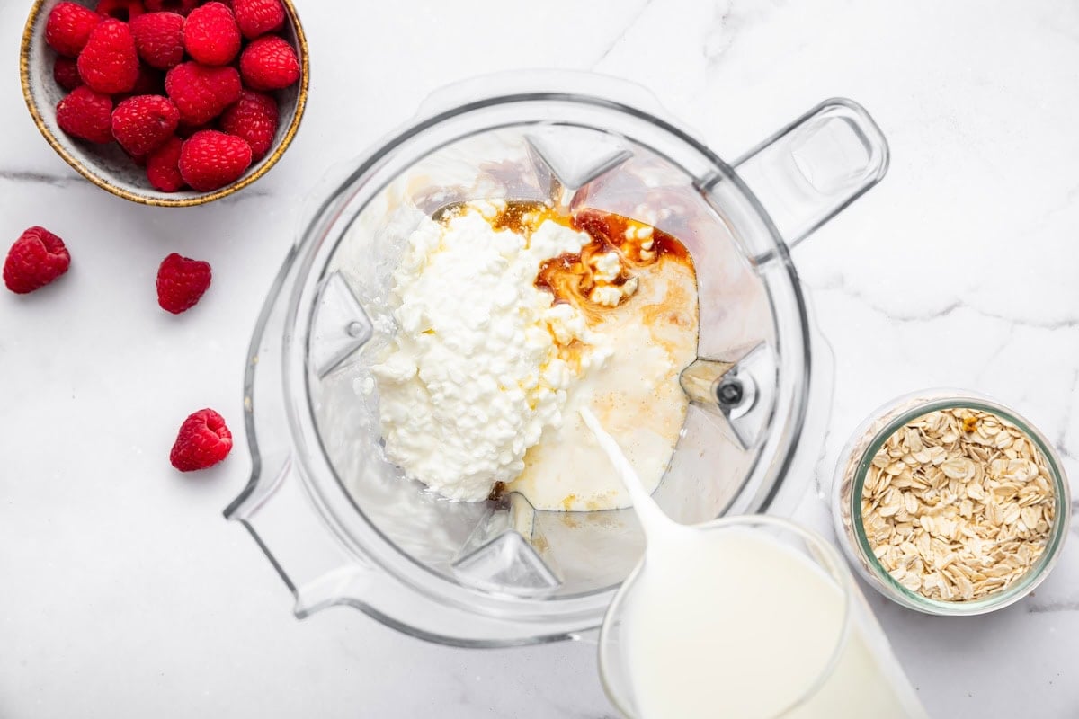 Blender with cottage cheese, almond milk, maple syrup and vanilla before blending.