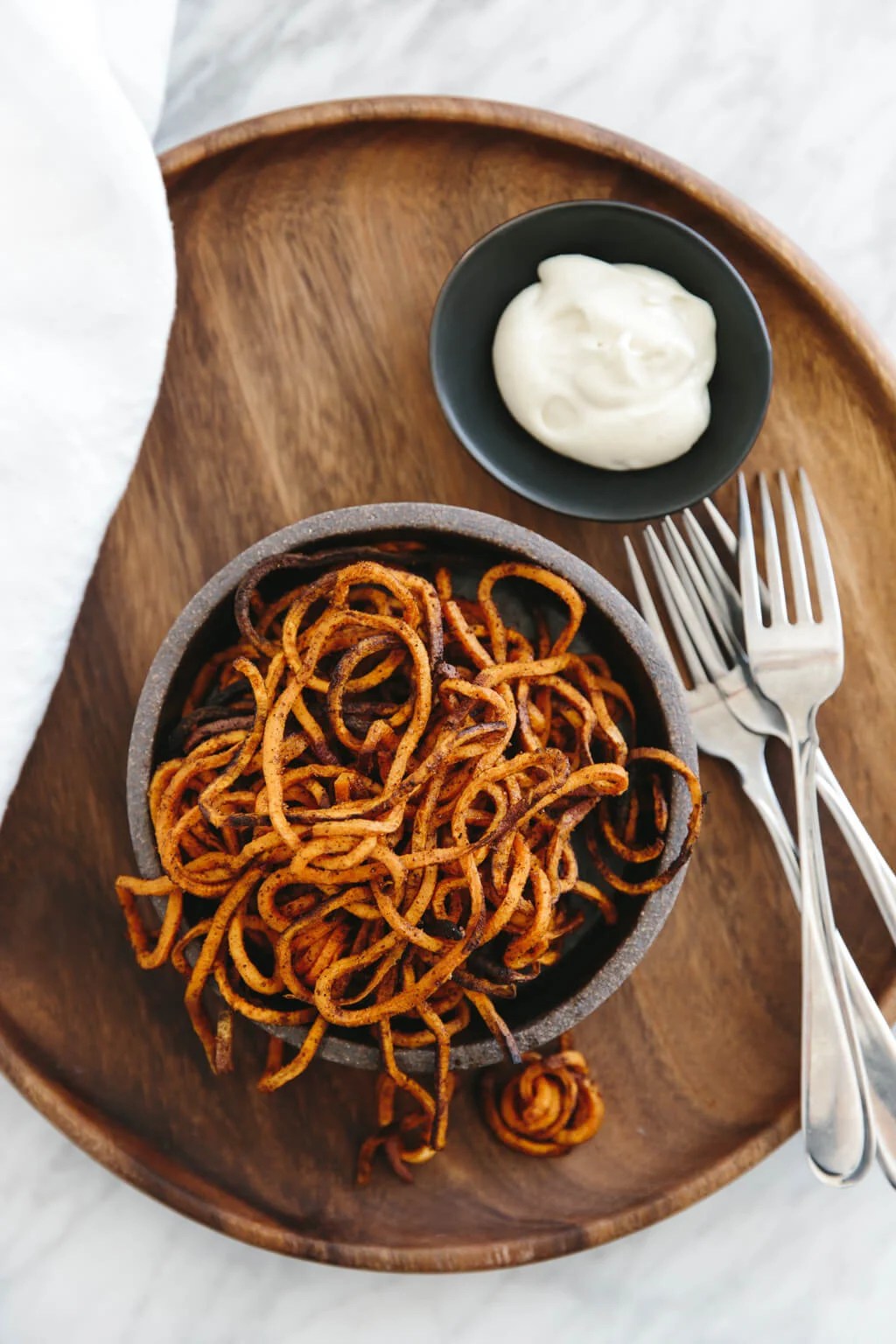 (gluten-free, paleo) Curly sweet potato fries are easily made with a spiralizer. They're seasoned with paprika and garlic powder and baked in the oven until perfectly crispy.