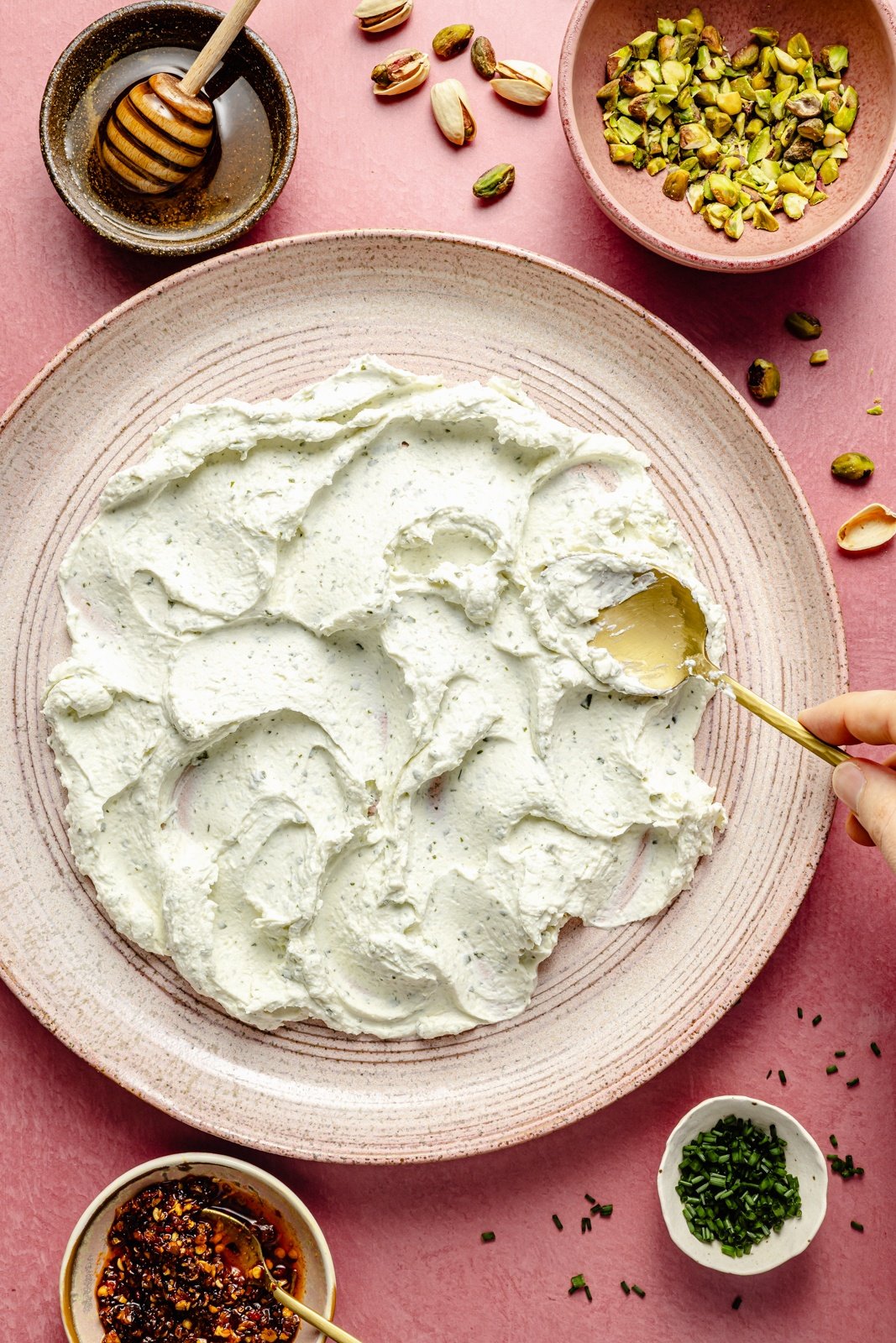 spreading cheese onto a platter to make chili crispy honey cheese dip