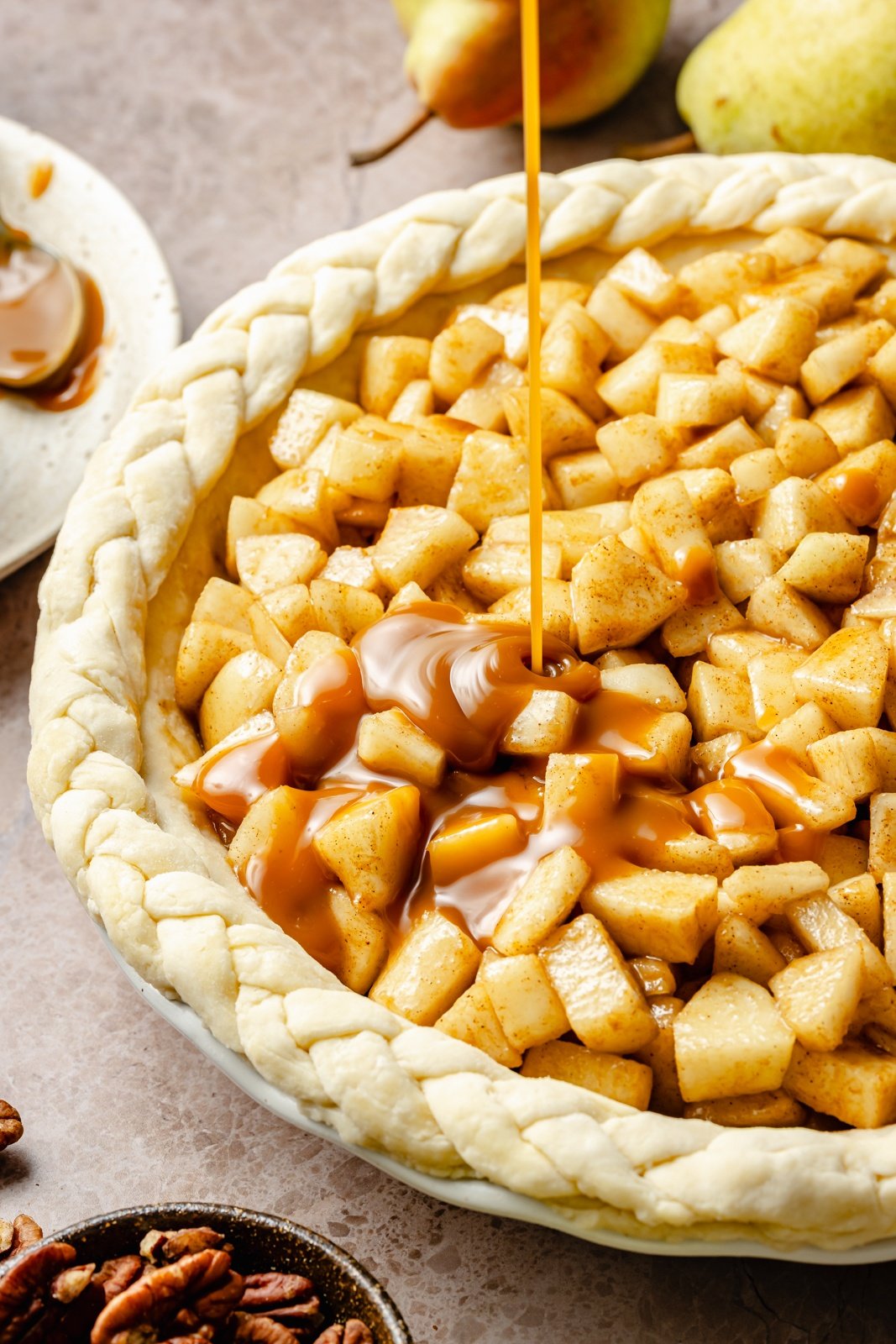 drizzling caramel onto the filling of a pear pie