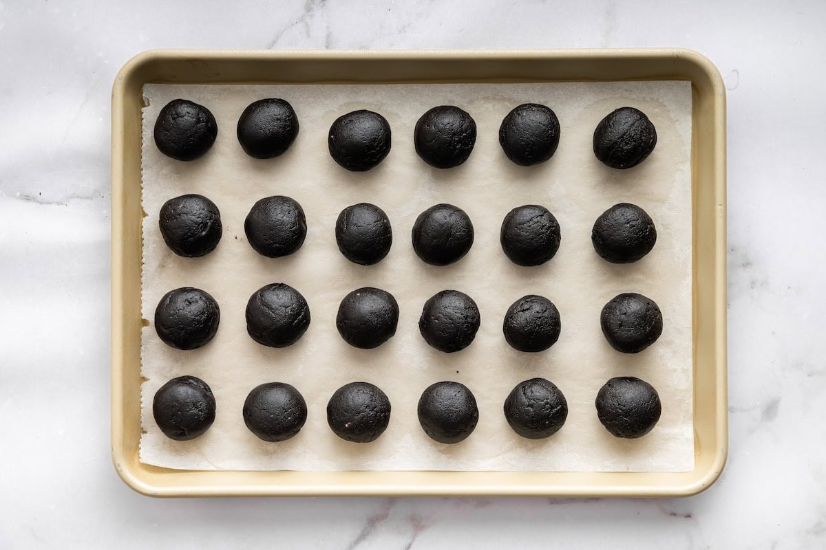 Smooth Oreo truffle balls lined up on a baking sheet ready for chilling.
