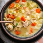 leftover turkey soup lifted on a spoon over a bowl.