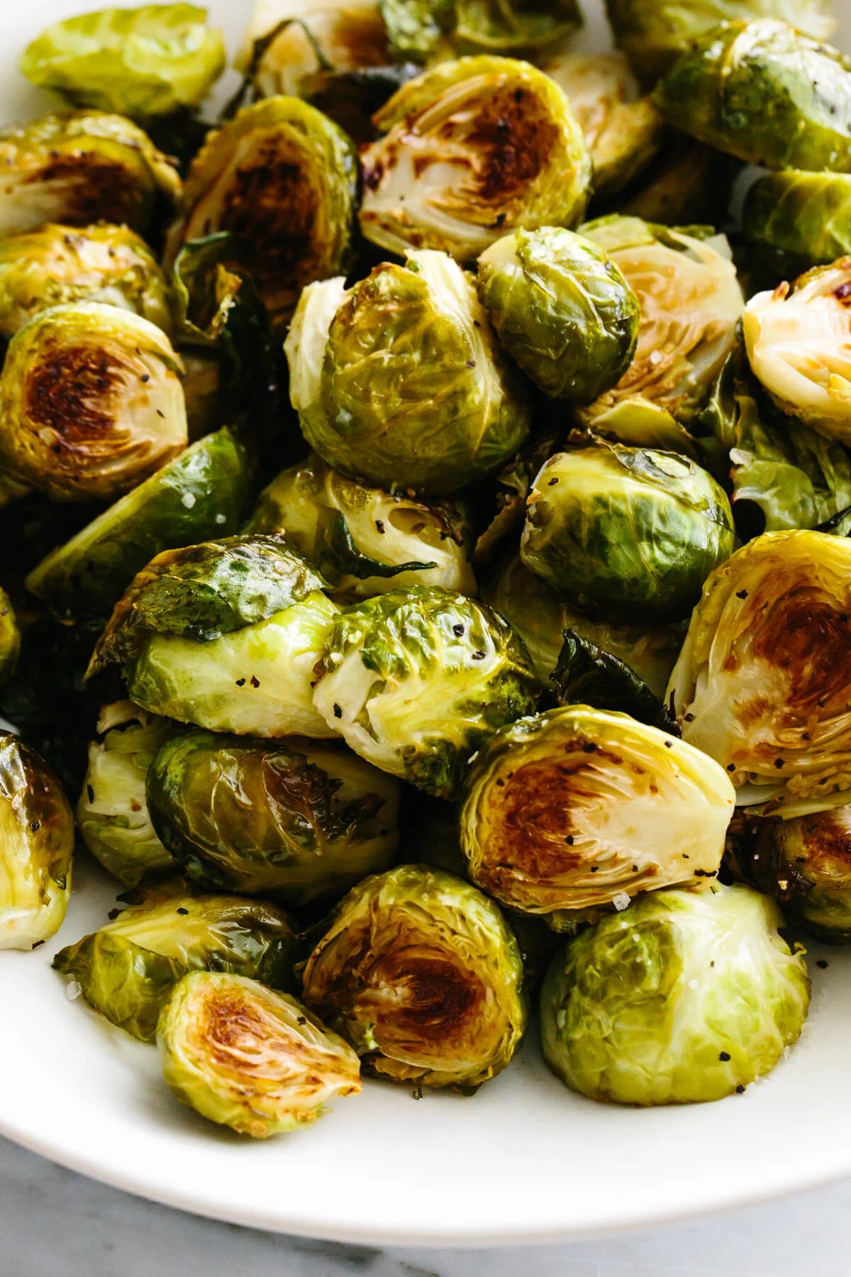 Roasted brussels sprouts in a large white bowl.
