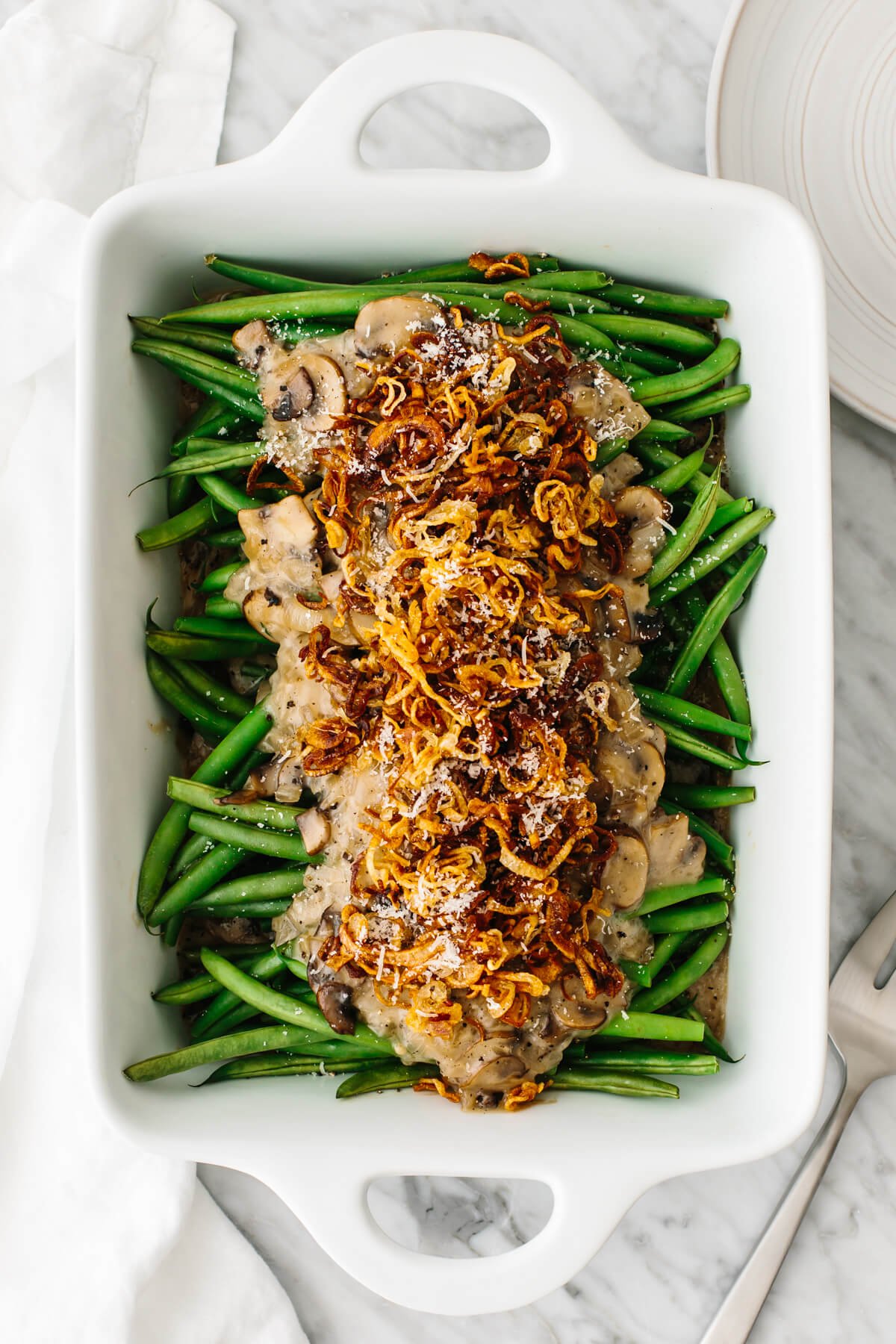 A white dish with green bean casserole in it.