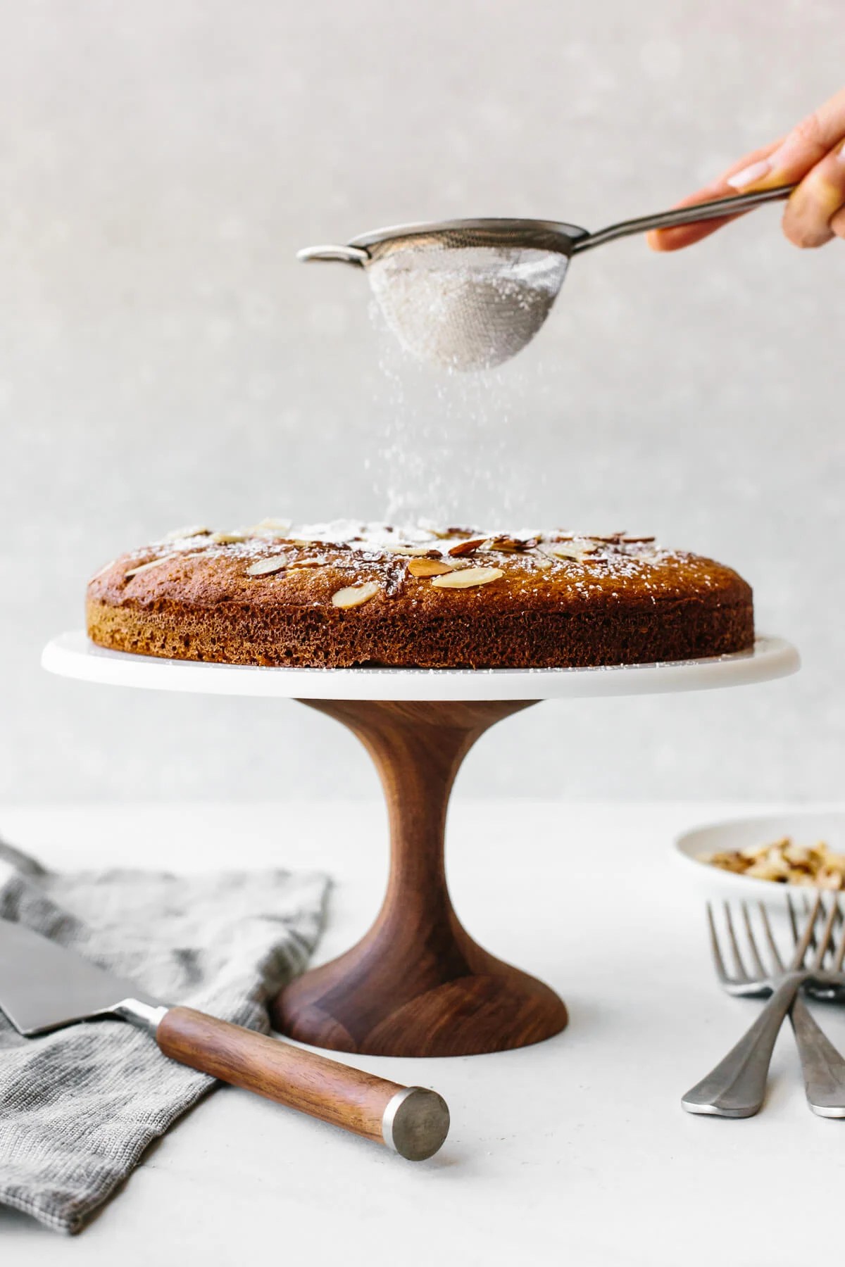Dusting powdered sugar on a cake
