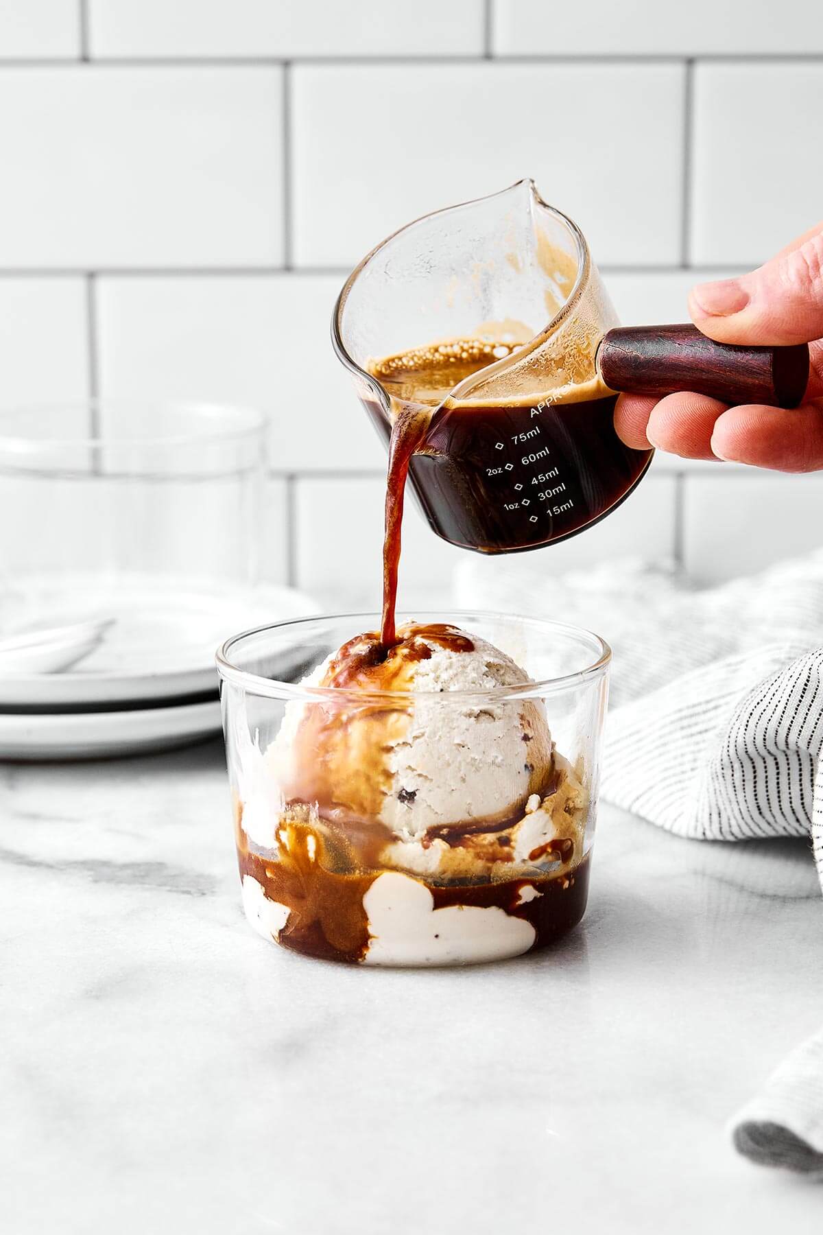 Pouring espresso into a glass cup of ice cream.