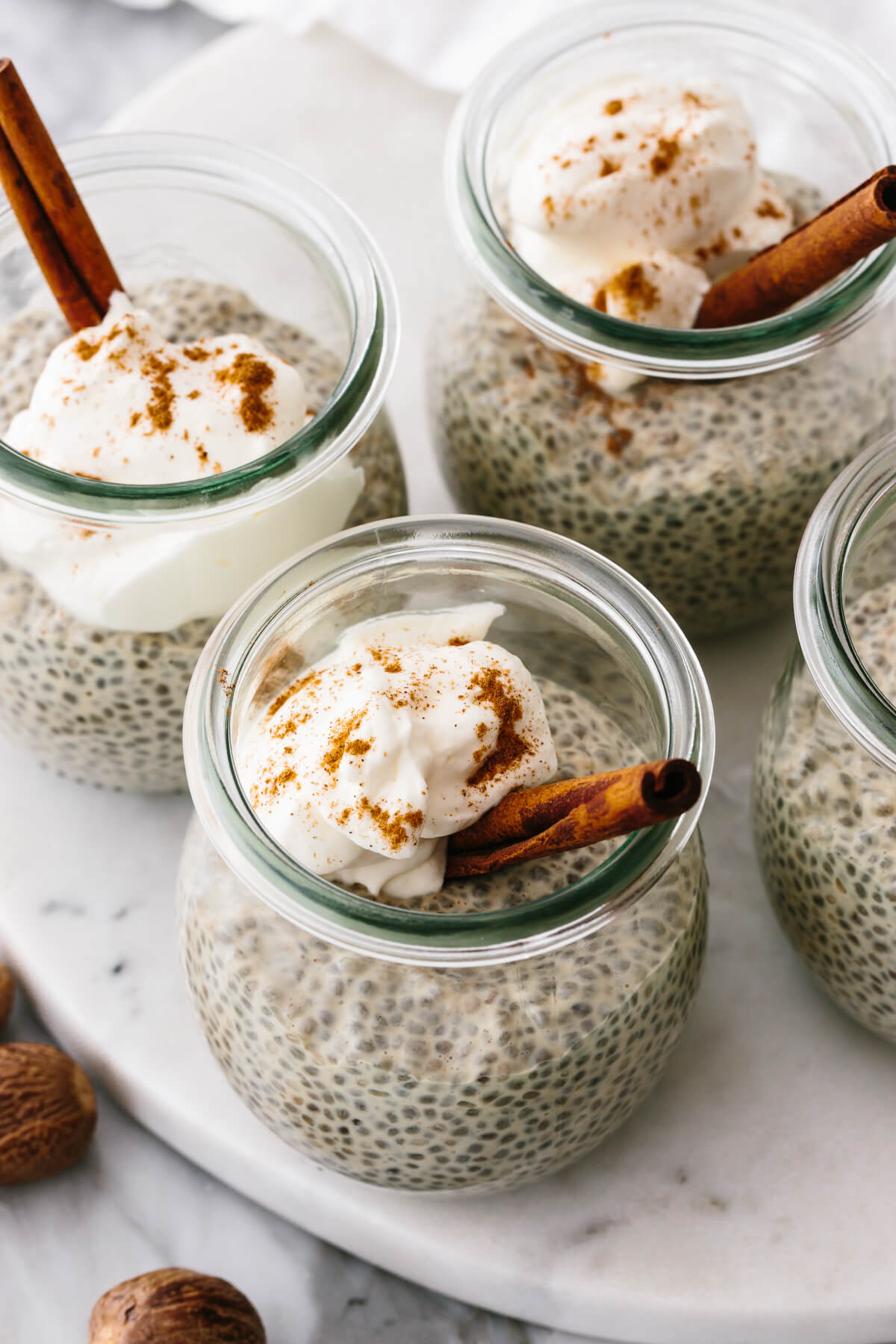 Glasses of eggnog chia pudding on a table with a spoon.