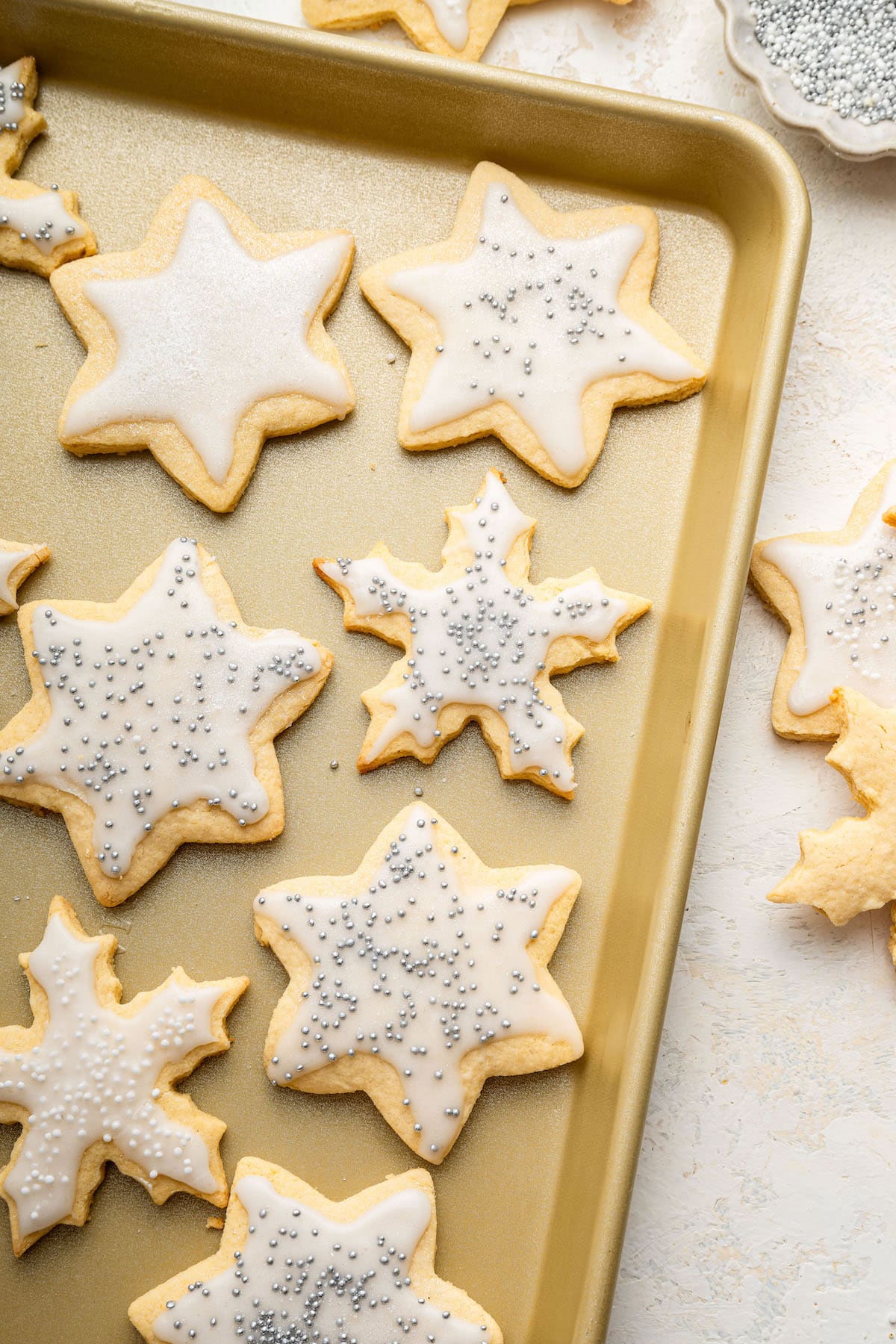 Gluten free sugar cookies decorated with icing on a baking sheet.