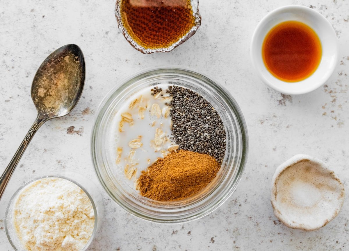 Ingredients for snickerdoodle overnight oats in a jar, including oats, chia seeds, cinnamon and milk.