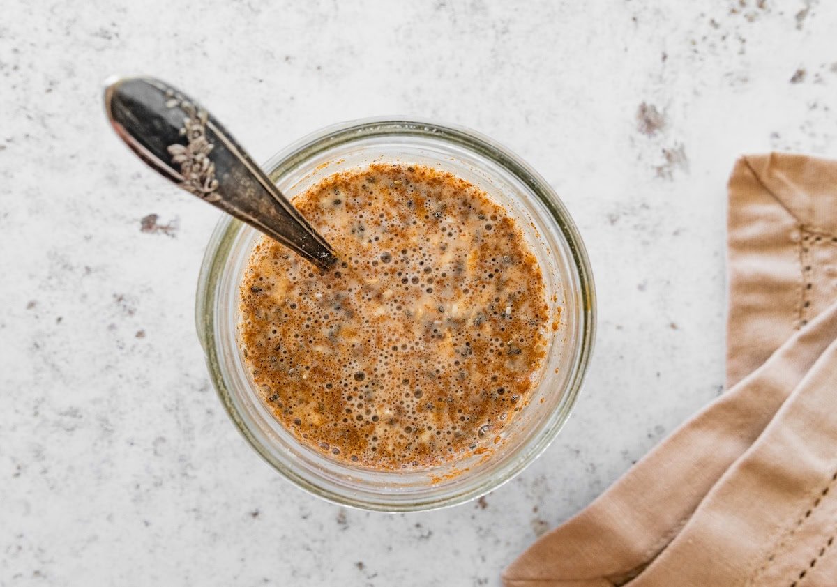 Jar of snickerdoodle overnight oats being stirred with a spoon.