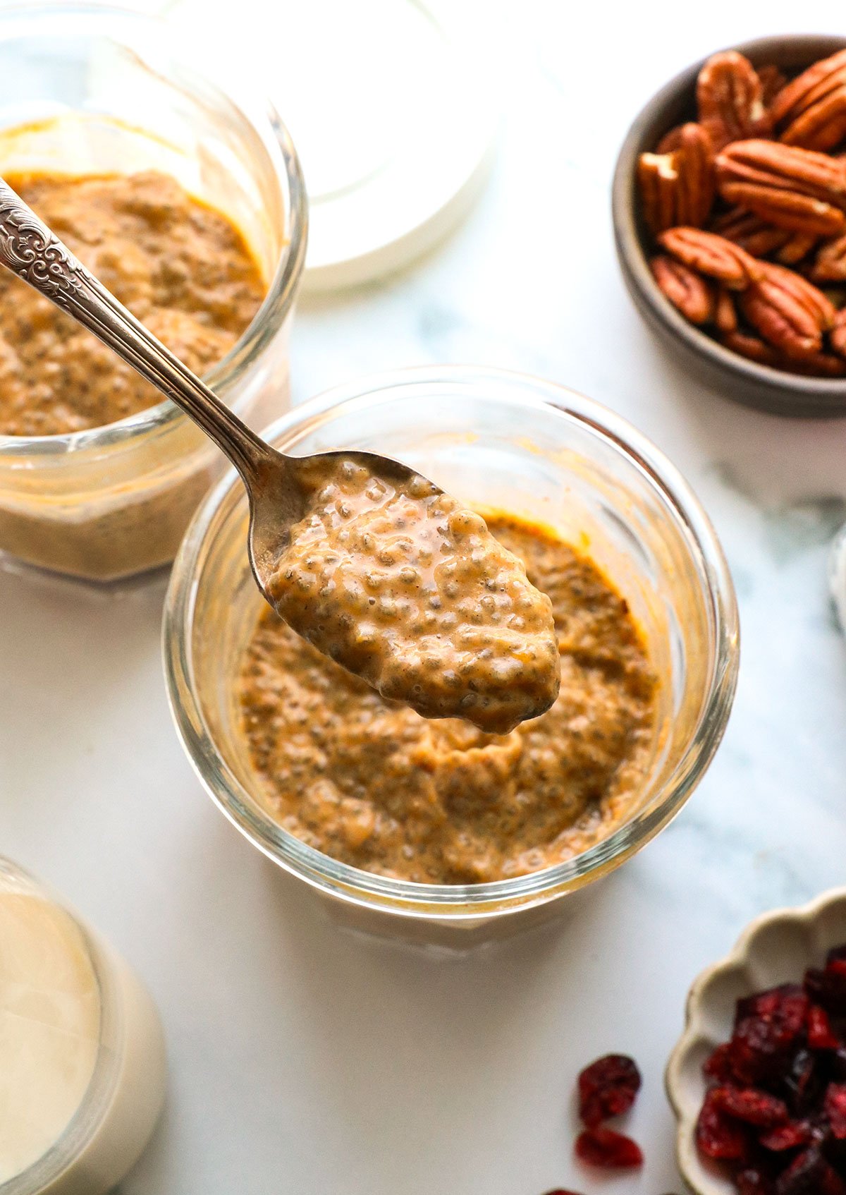 pumpkin chia pudding lifted on a spoon from a jar. 