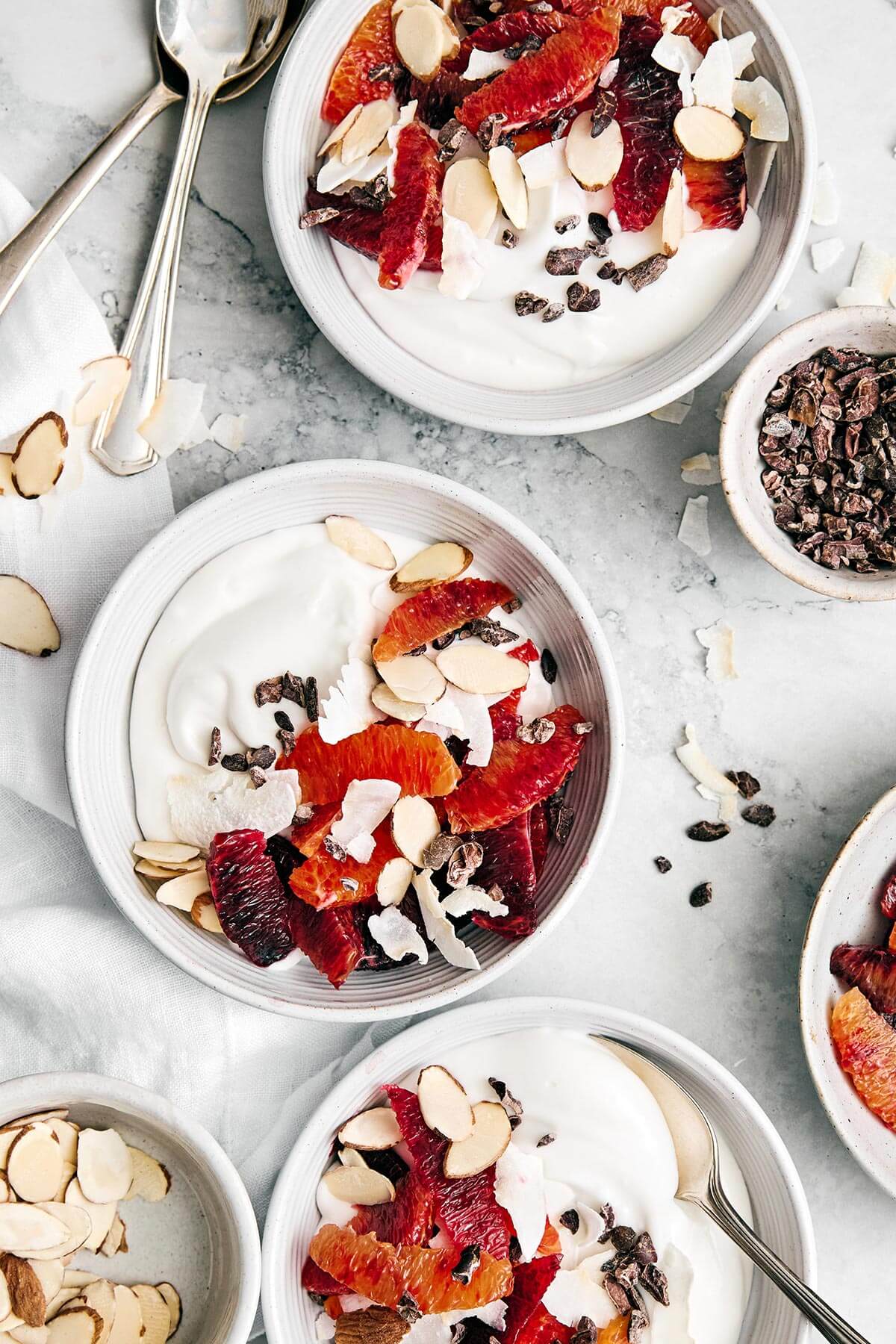Coconut yogurt bowls with fruit and cacao nibs.