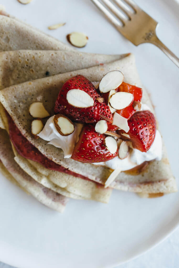 (gluten-free, paleo) Vanilla bean cassava flour crepes with strawberry chia jam. Sweet breakfast crepes are filled with homemade strawberry chia jam and topped with coconut whipped cream and almonds.