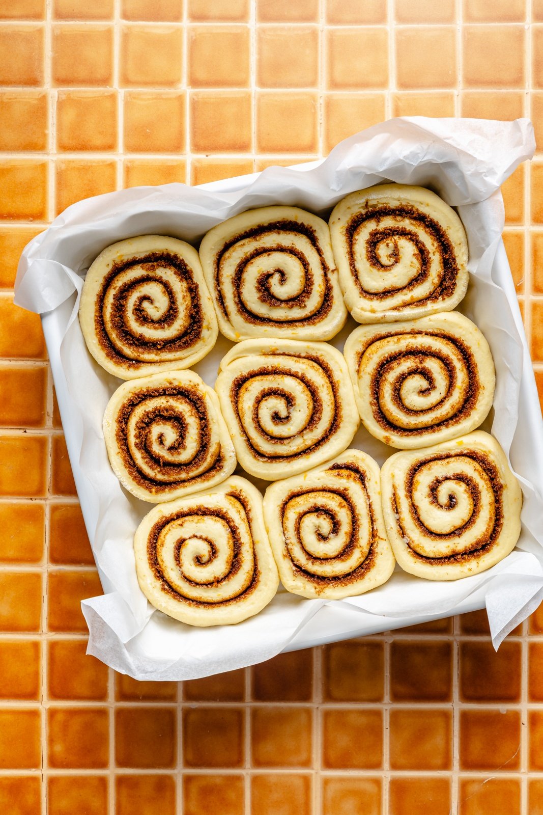 unbaked orange rolls in a square pan